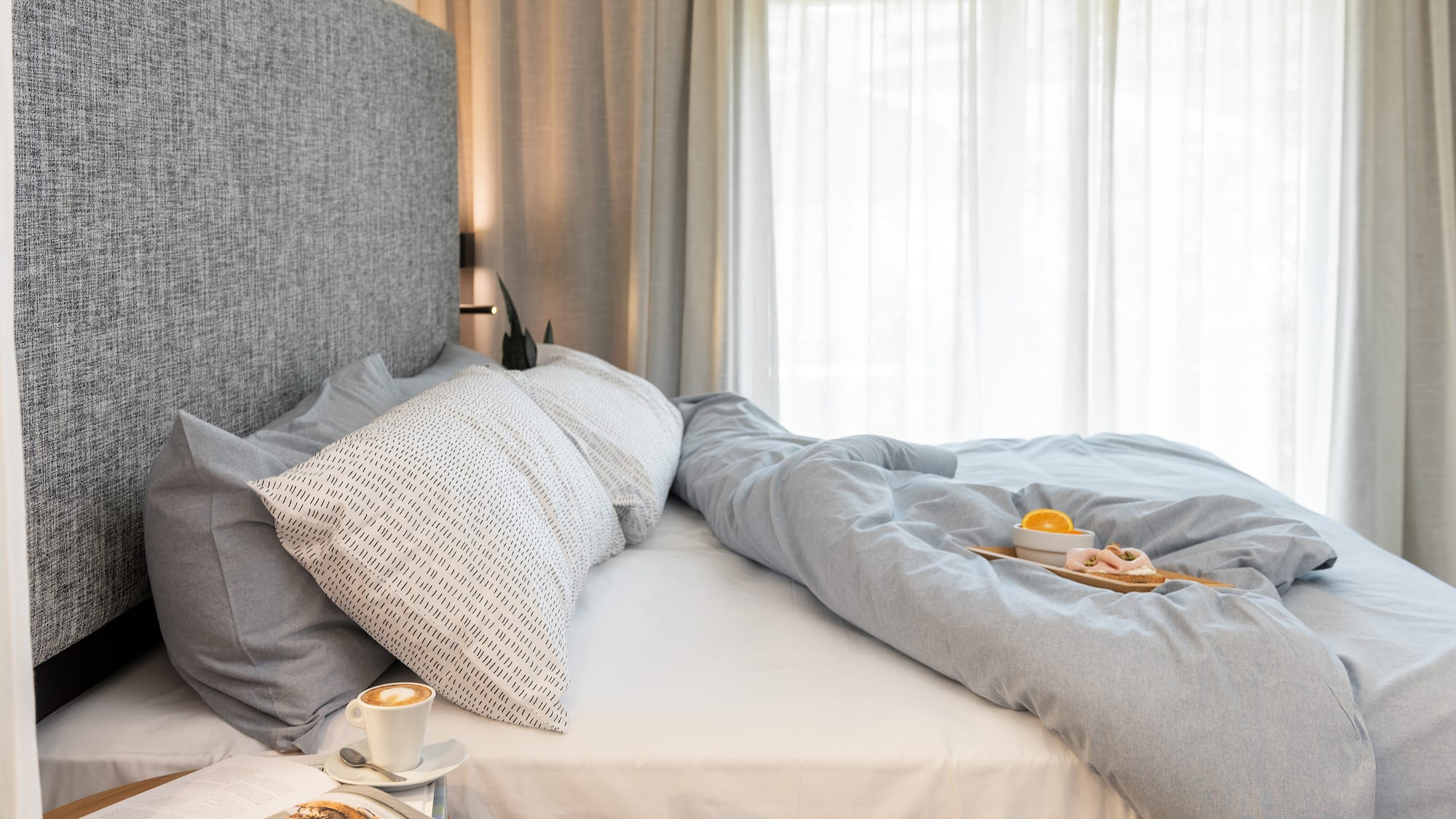 a bed with a tray of coffee and a plate of food