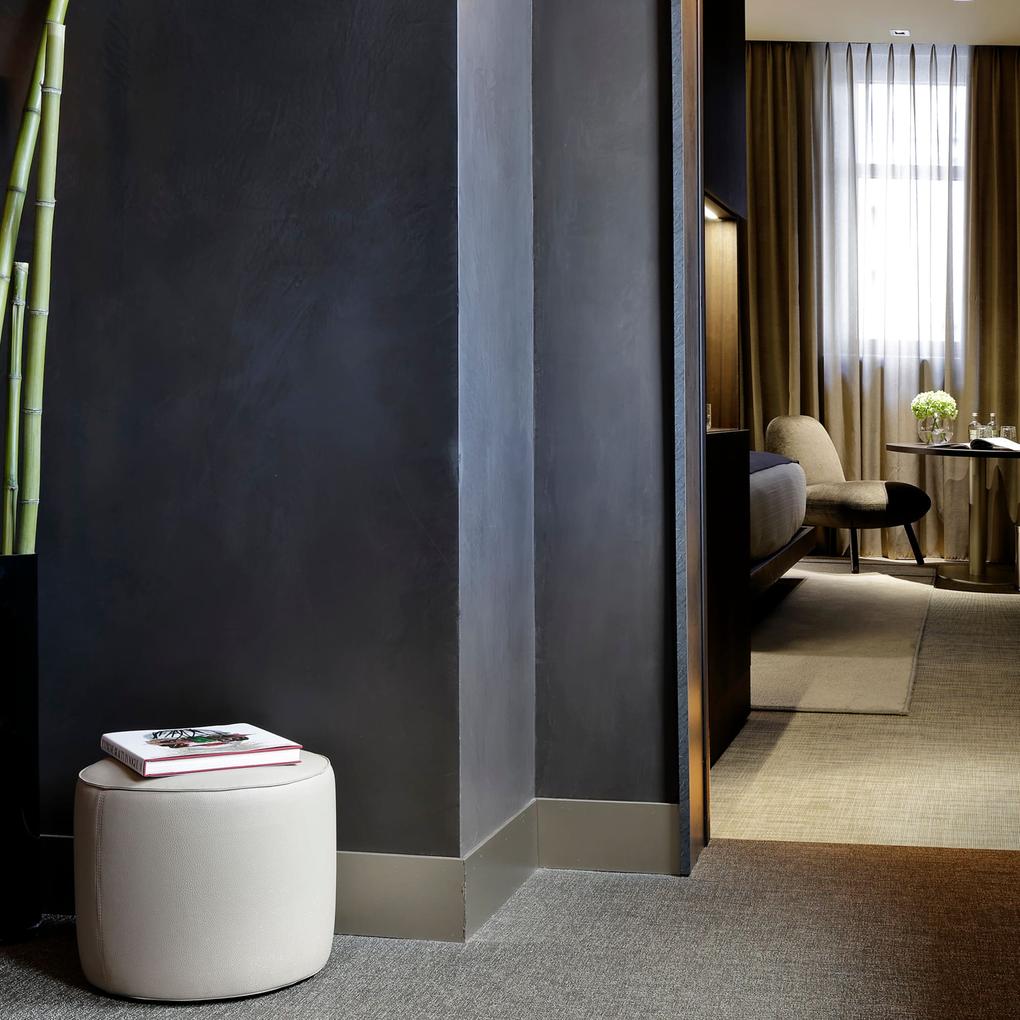 a room with a tall plant and a round stool