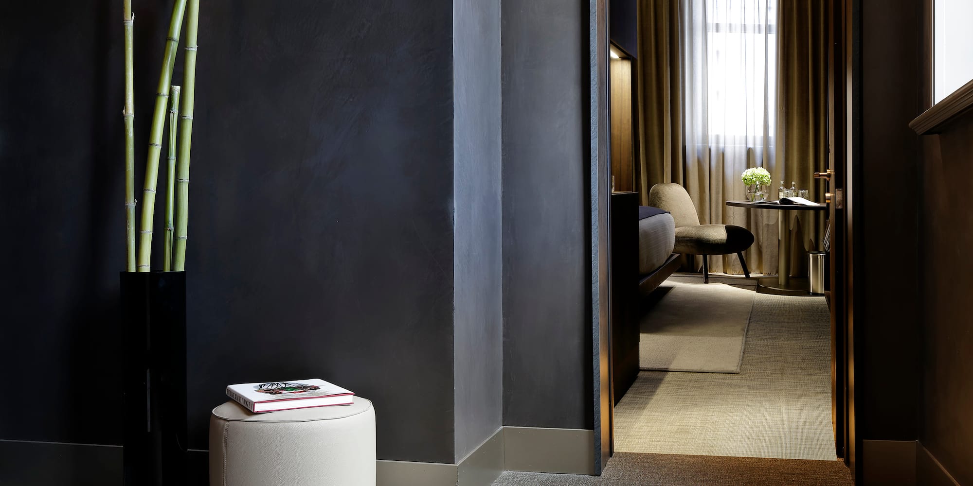 a room with a tall plant and a round stool