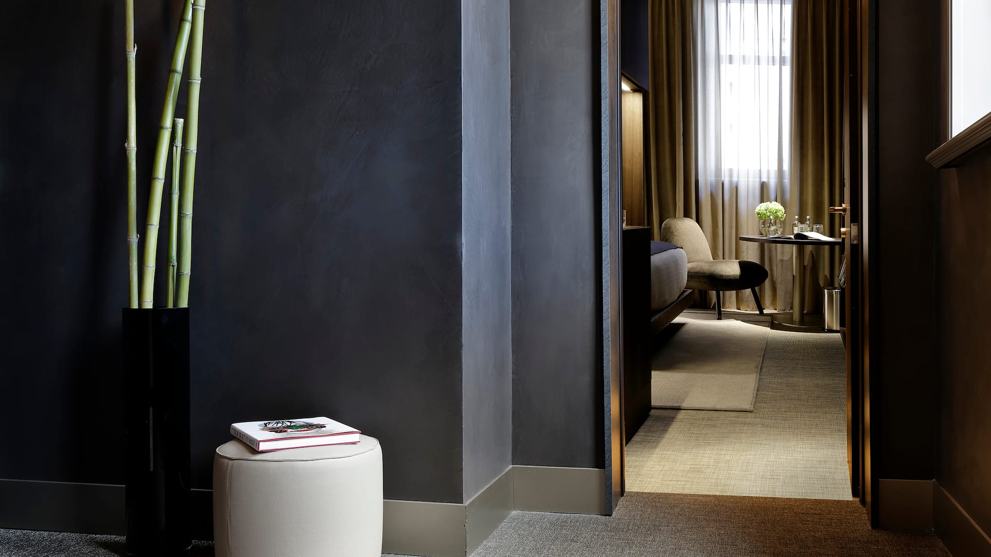 a room with a tall plant and a round stool