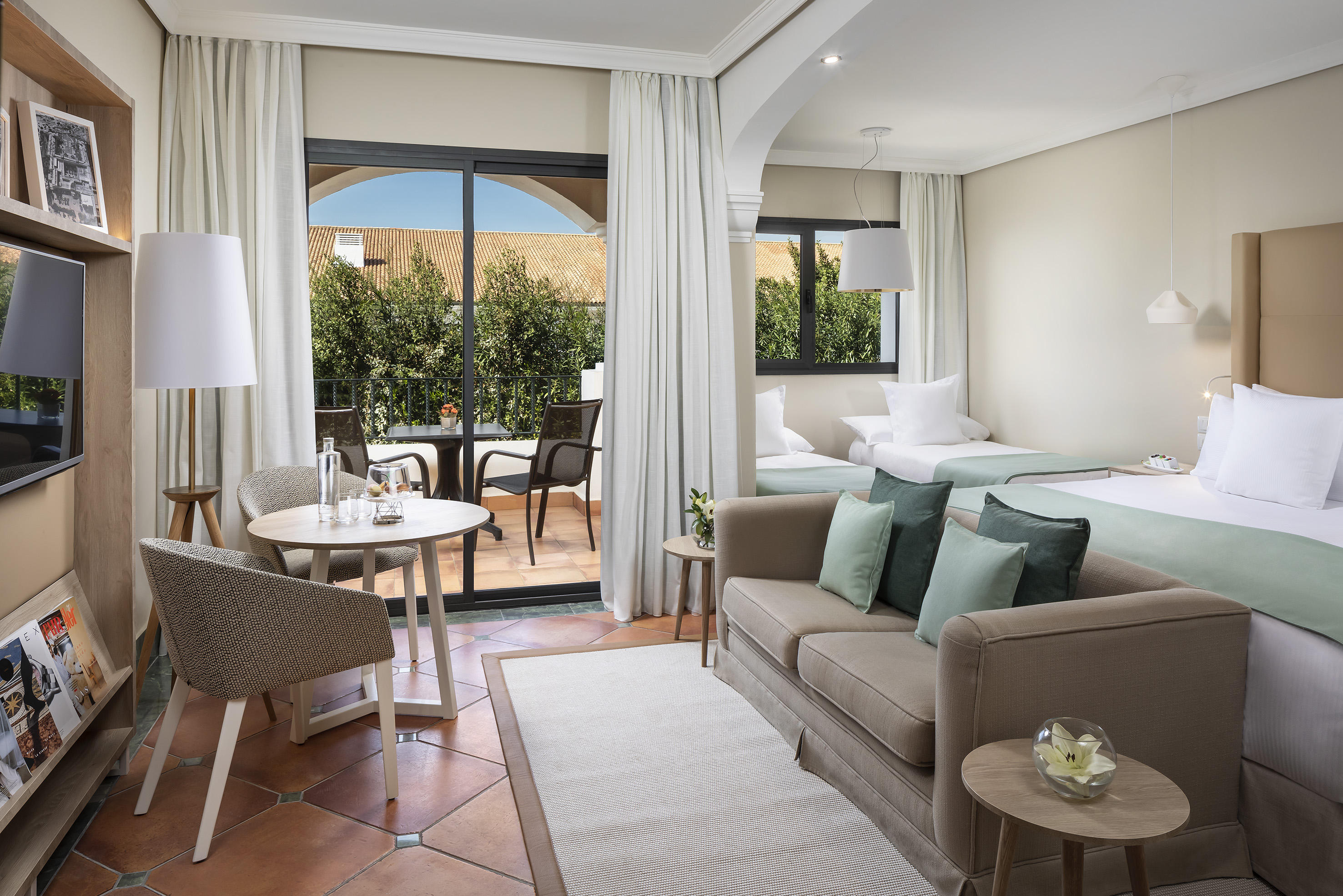Spacious hotel suite with living area, twin beds, and a private balcony.