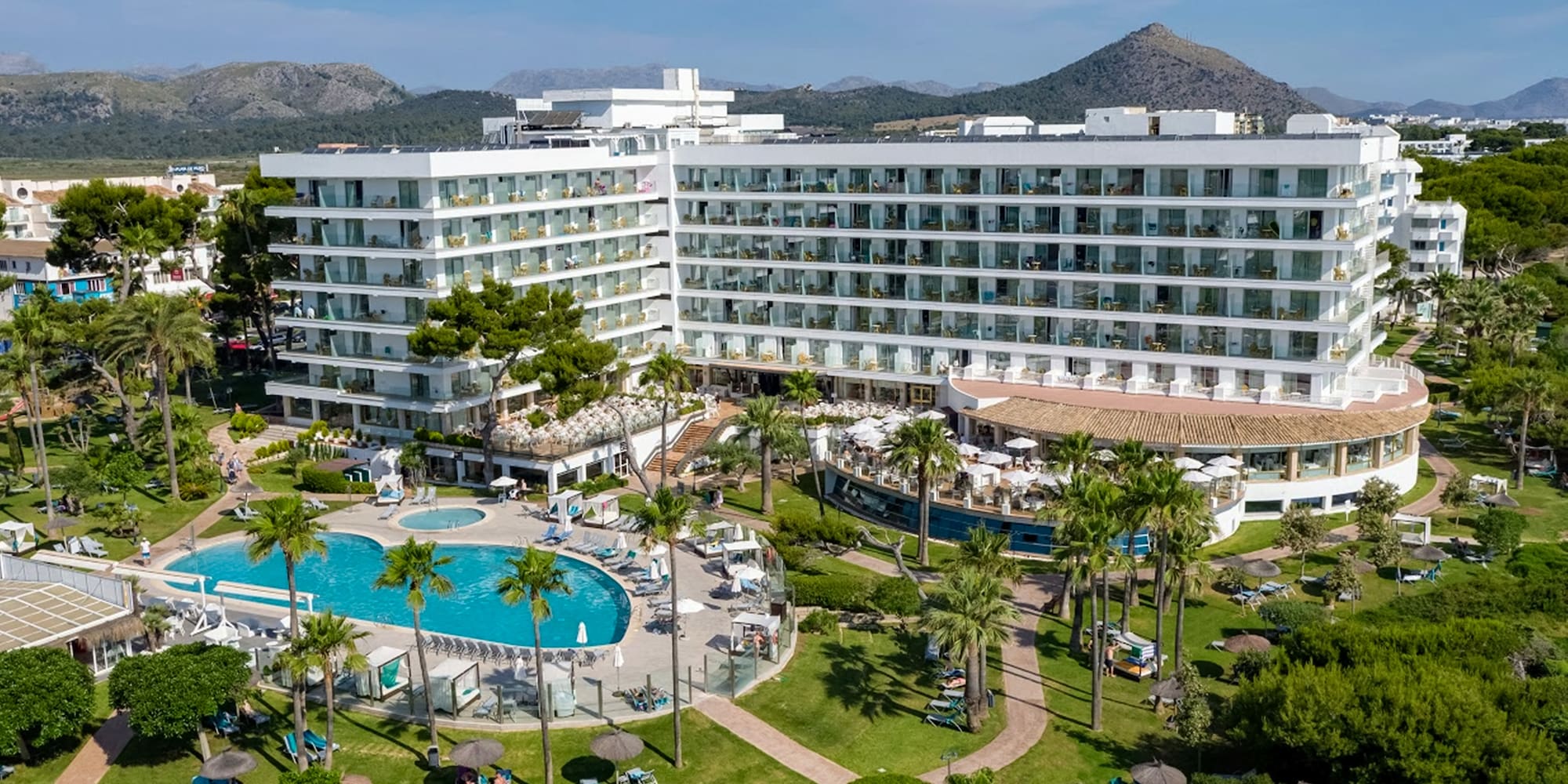 a large white building with a pool and trees
