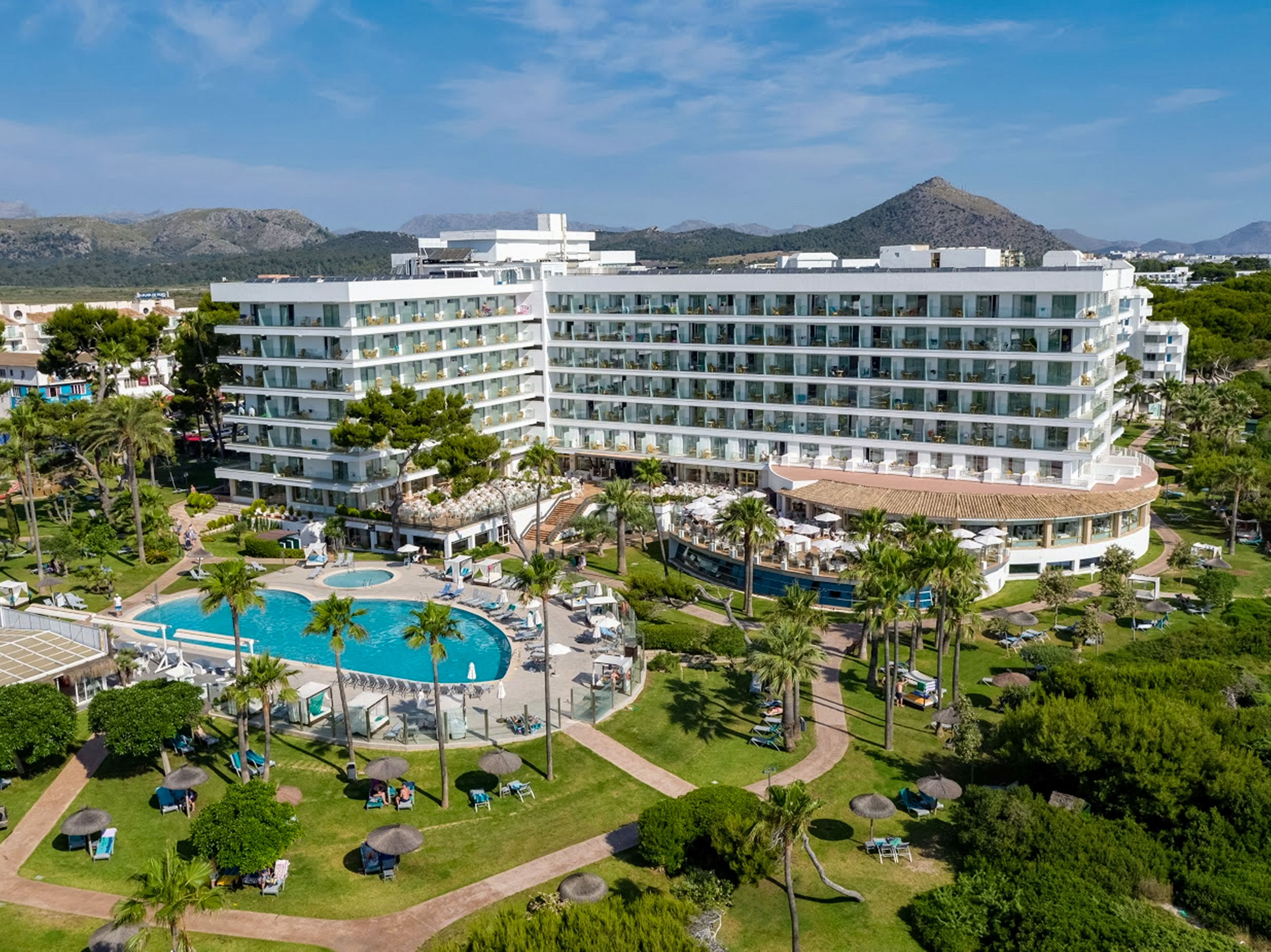 a large white building with a pool and trees