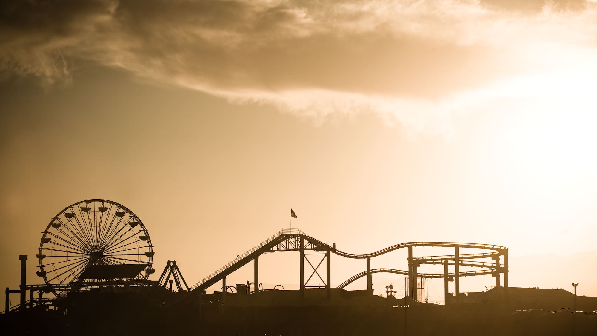 a silhouette of a roller coaster and a ferris wheel
