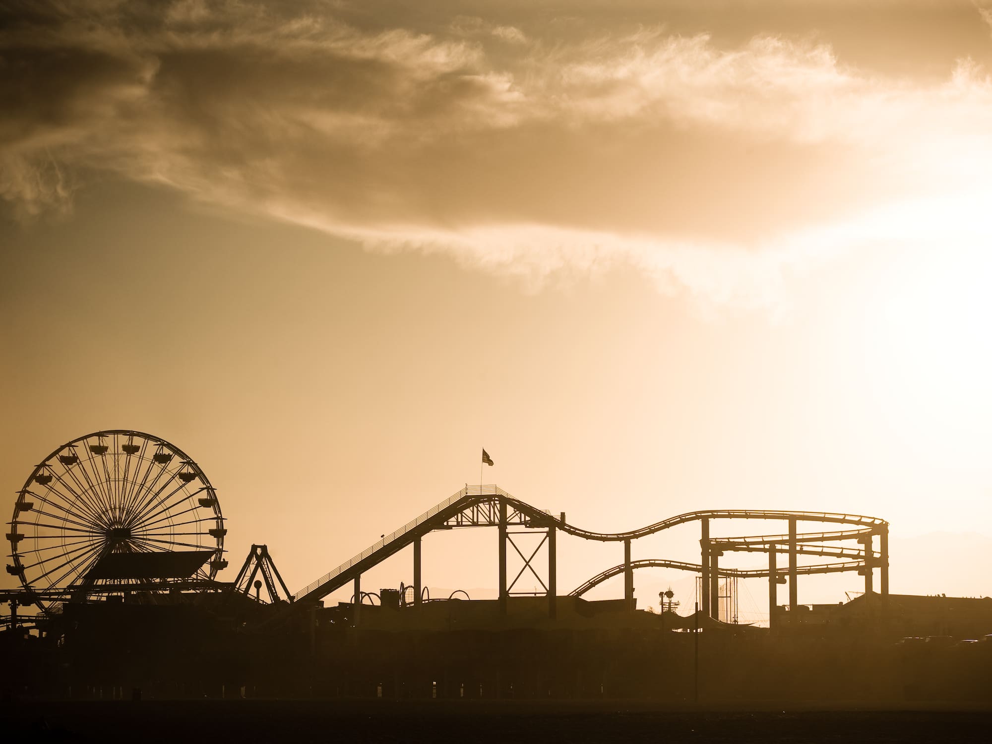 a silhouette of a roller coaster and a ferris wheel