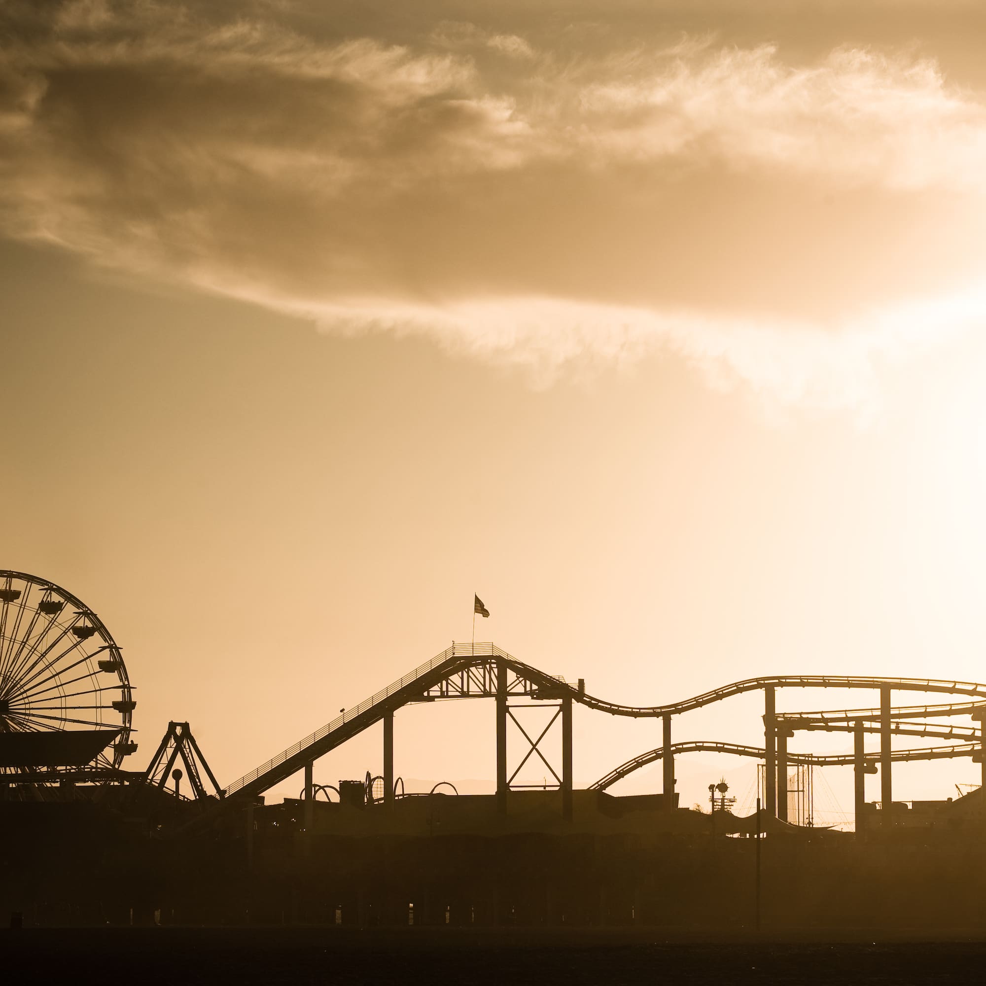 a silhouette of a roller coaster and a ferris wheel