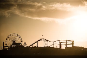 a silhouette of a roller coaster and a ferris wheel