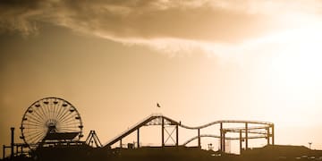 a silhouette of a roller coaster and a ferris wheel