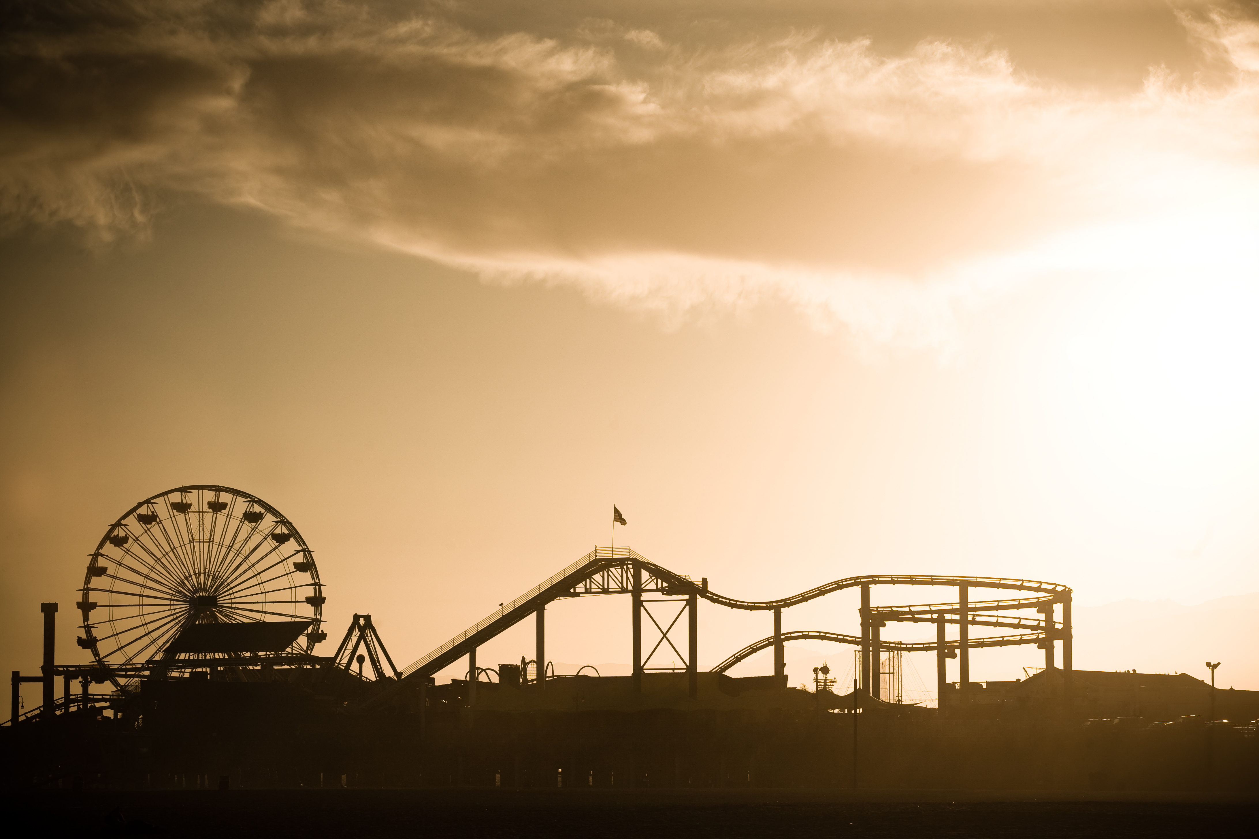 a silhouette of a roller coaster and a ferris wheel
