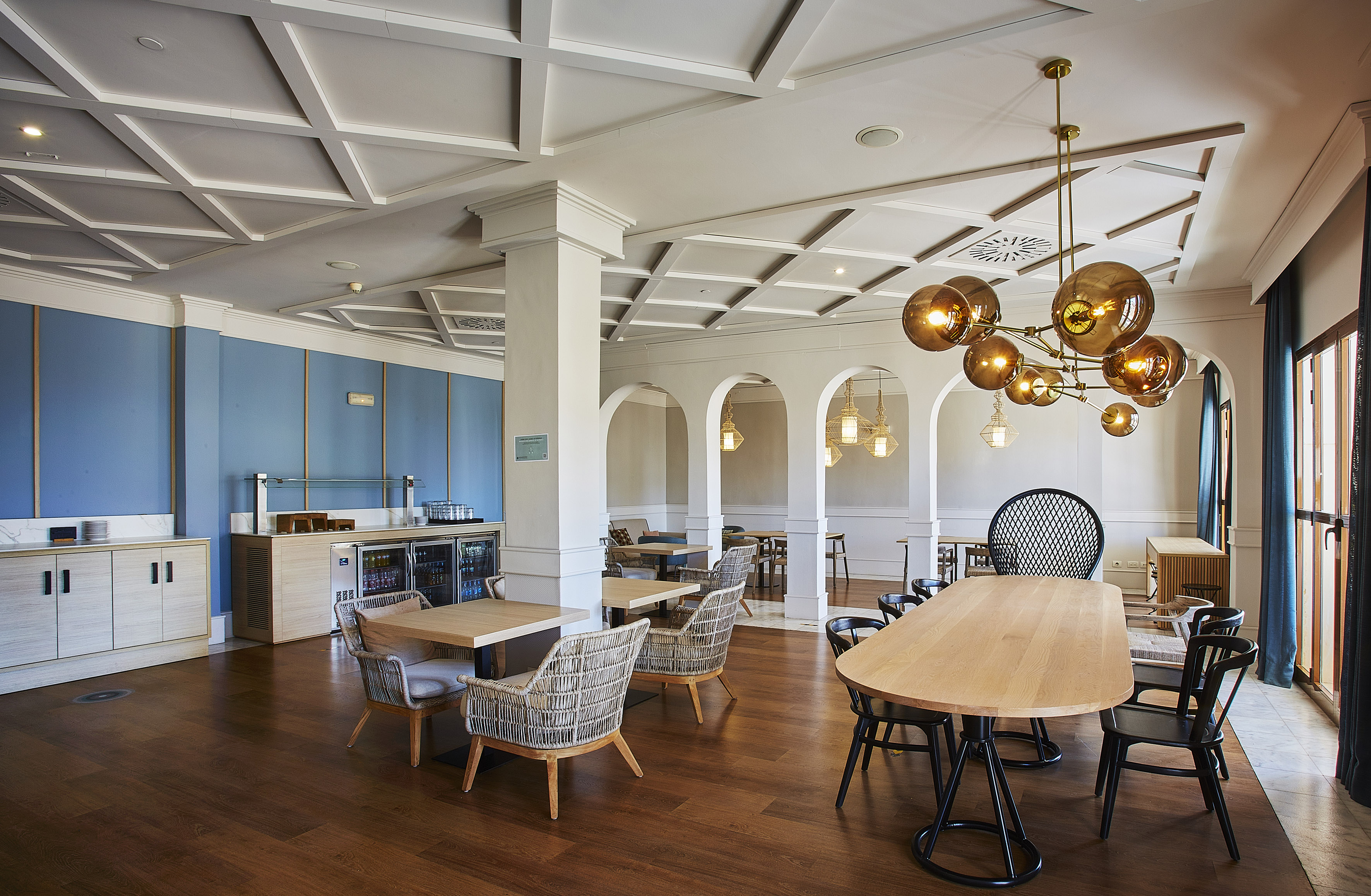 Modern hotel dining area with buffet, coffered ceiling, and stylish seating.