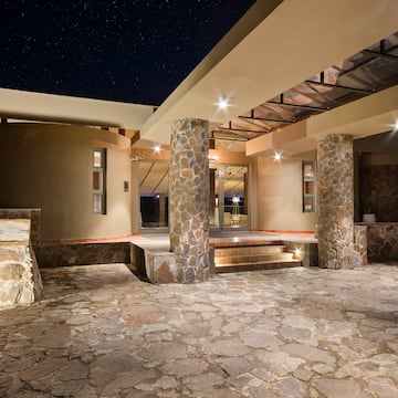 a stone patio with pillars and a walkway at night
