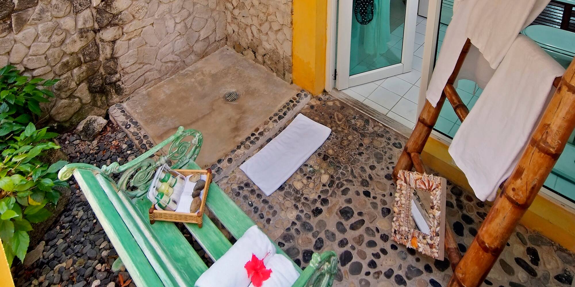a shower with a green bench and towels on it