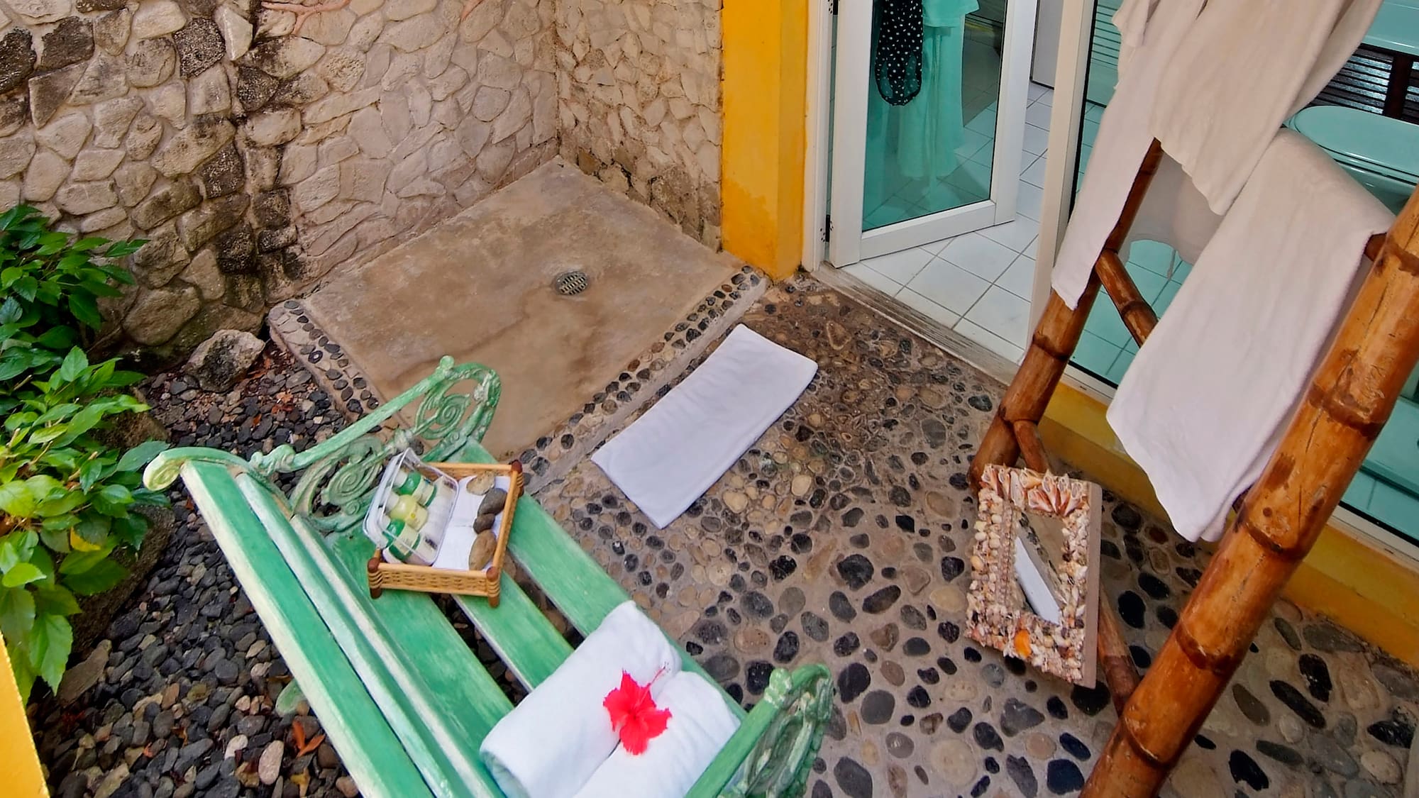 a shower with a green bench and towels on it