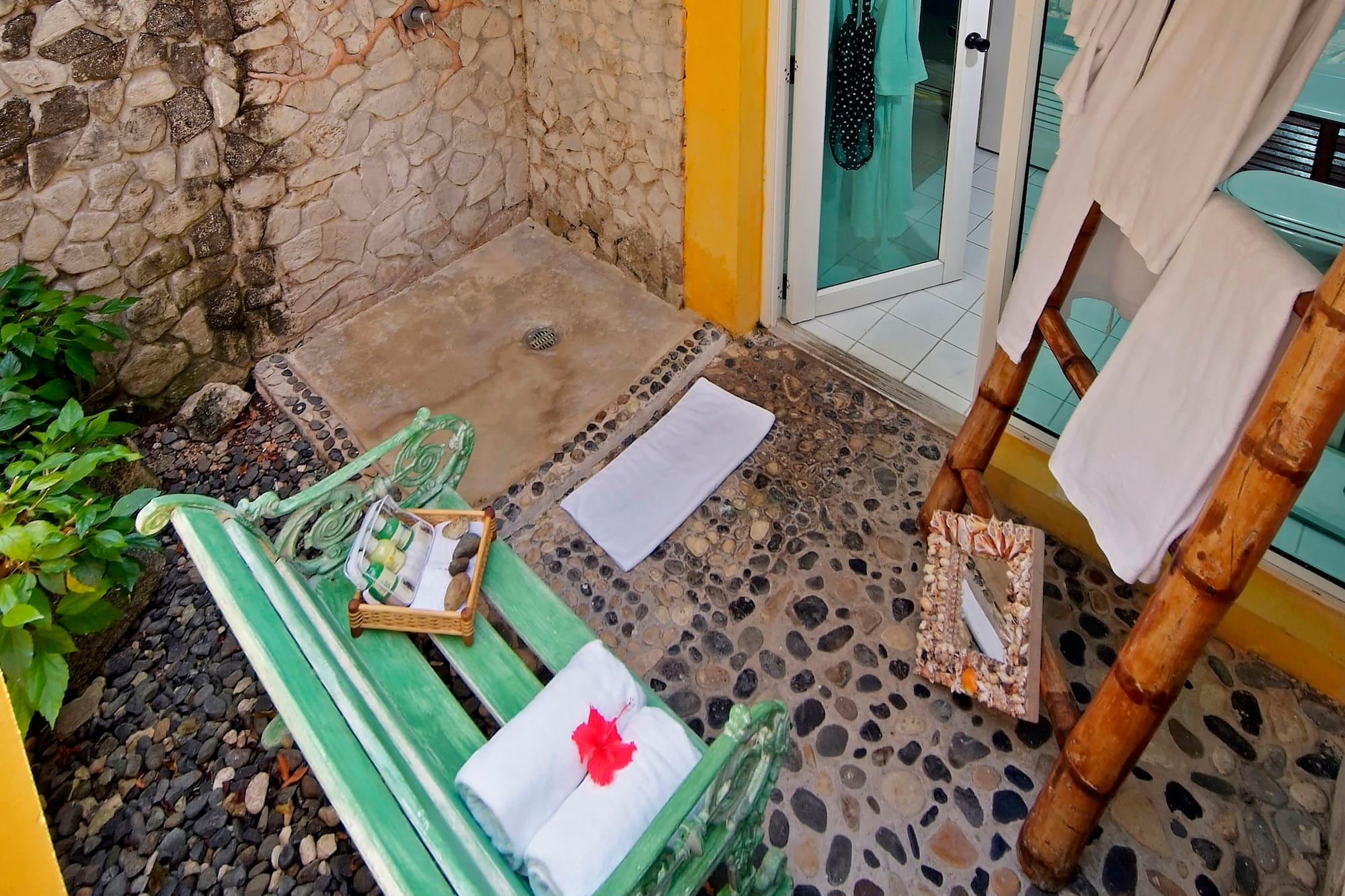 a shower with a green bench and towels on it