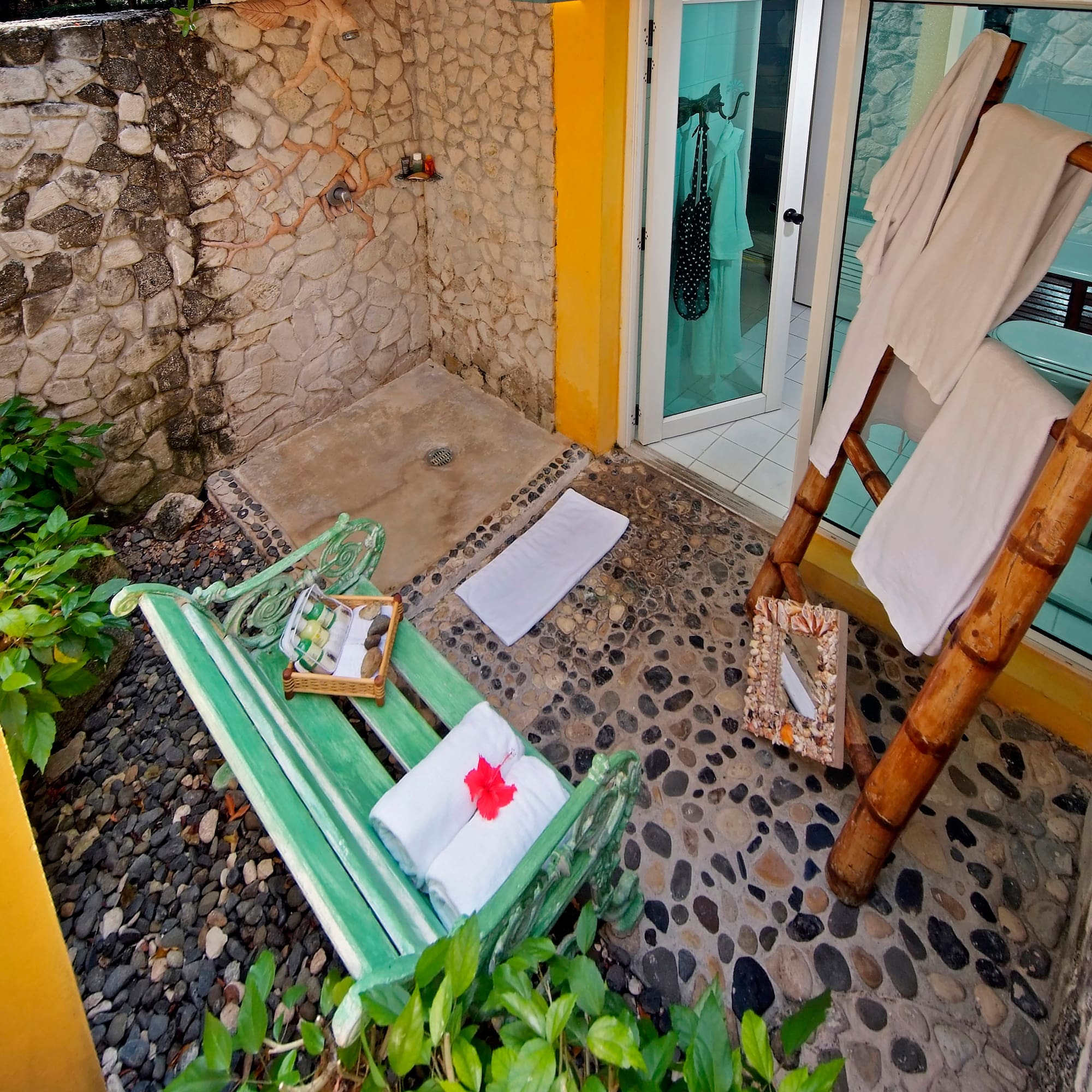 a shower with a green bench and towels on it