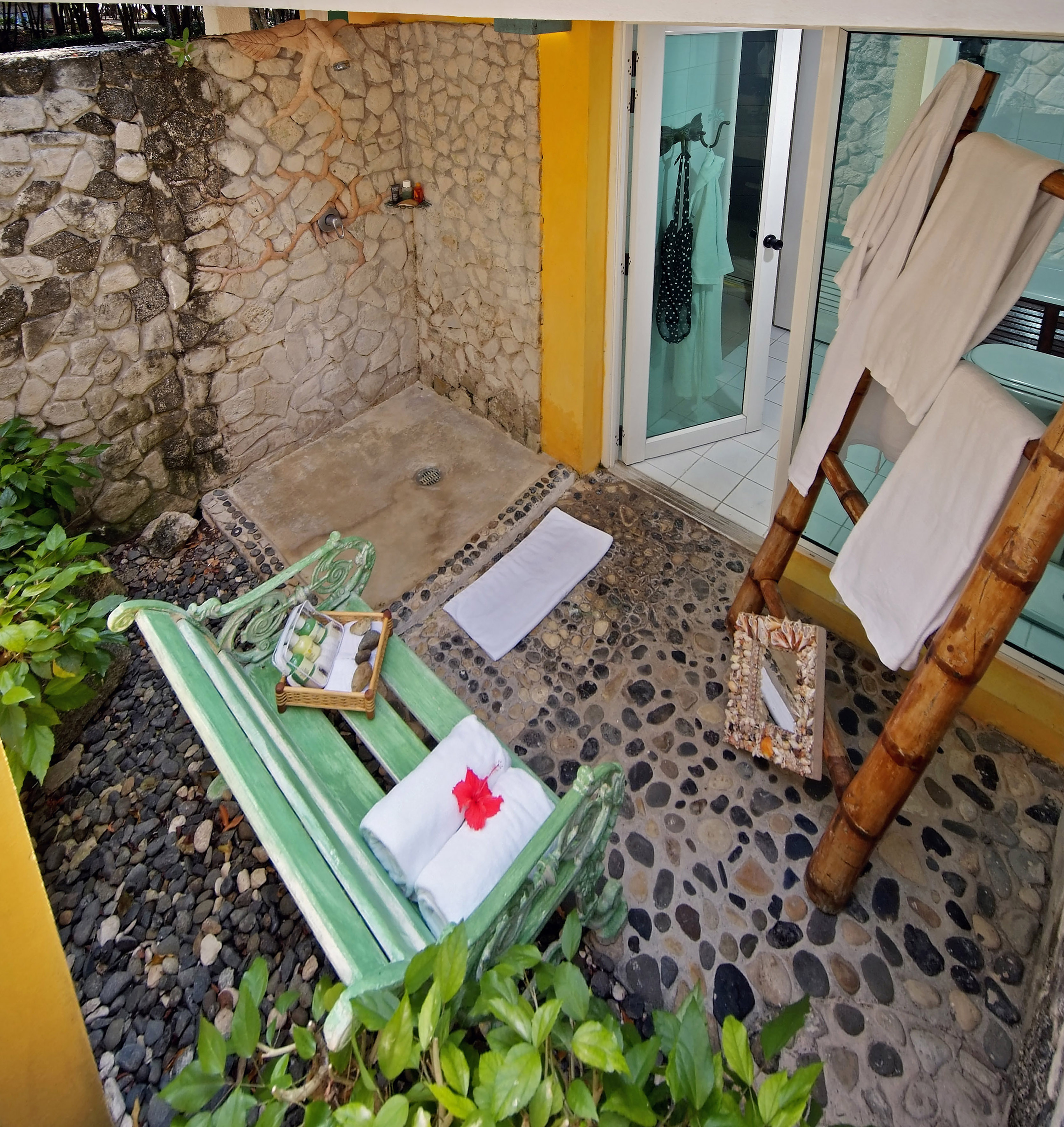 a shower with a green bench and towels on it