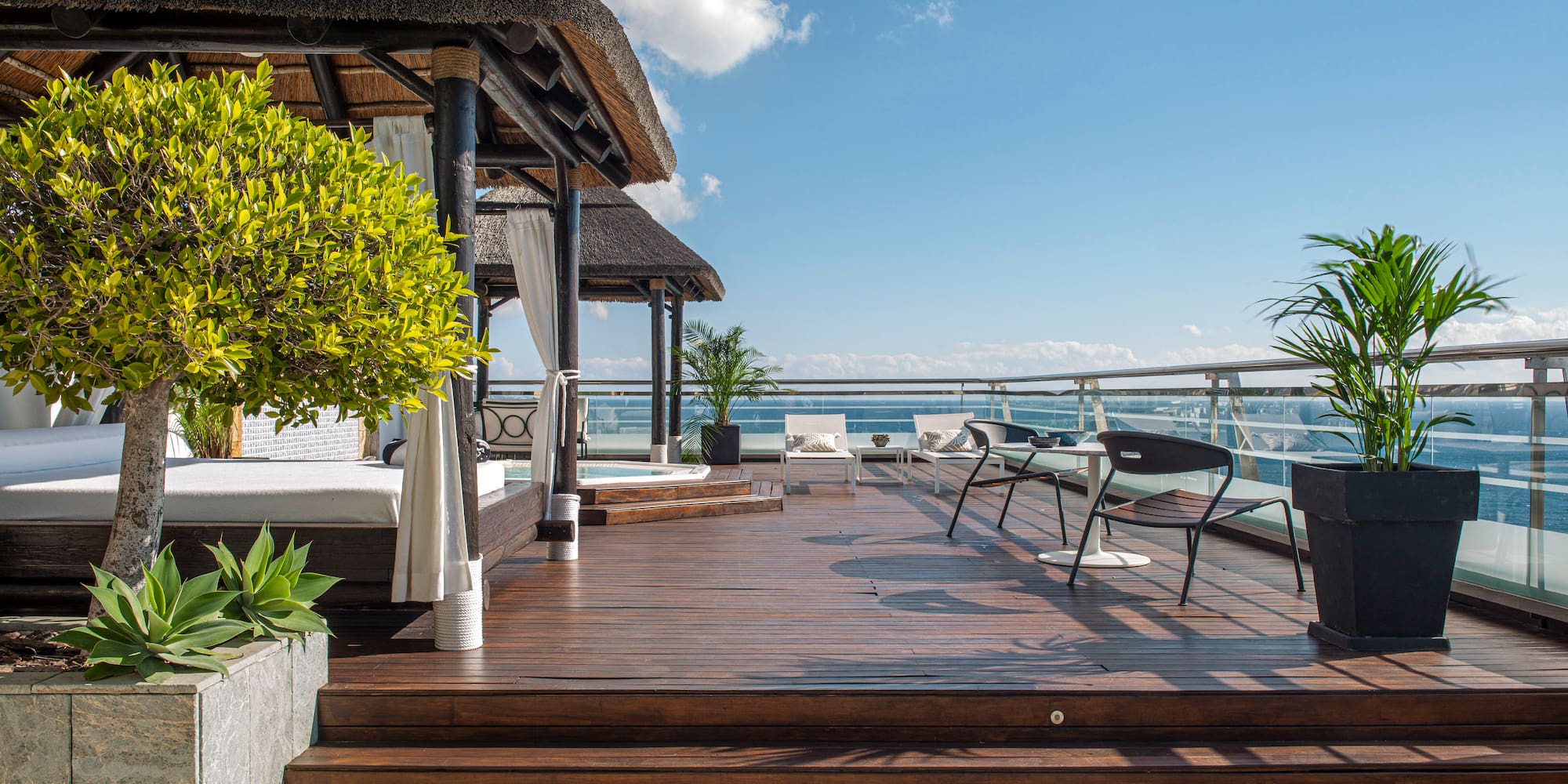 a deck with a thatched roof and a thatched umbrella and chairs