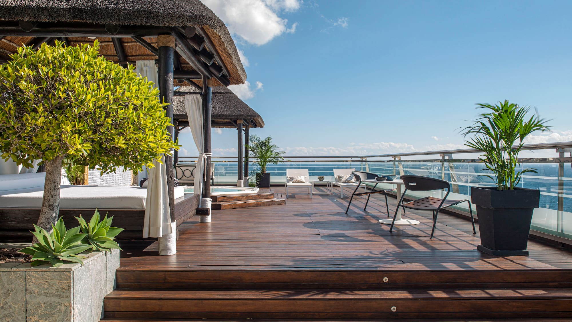 a deck with a thatched roof and a thatched umbrella and chairs