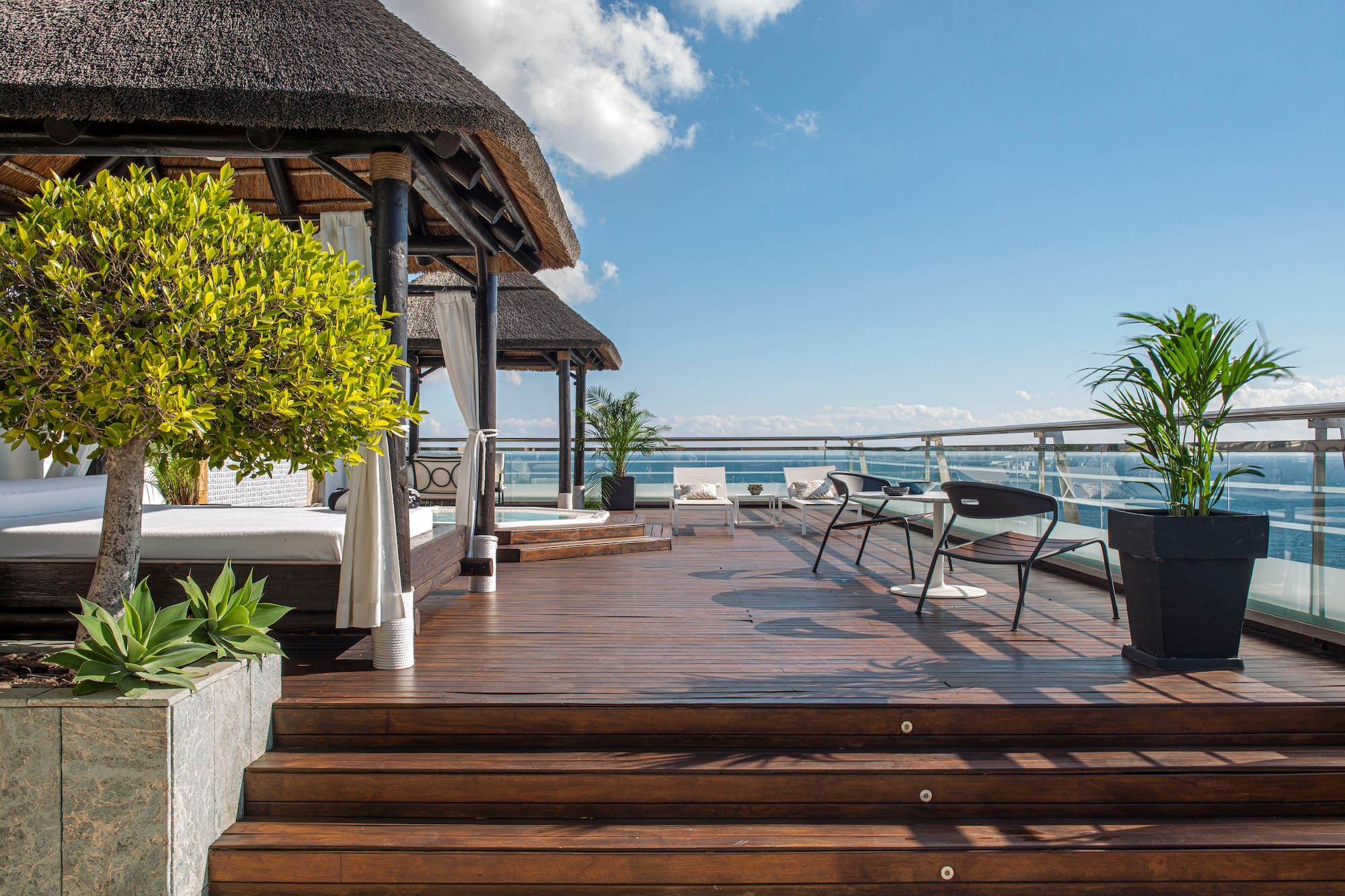 a deck with a thatched roof and a thatched umbrella and chairs