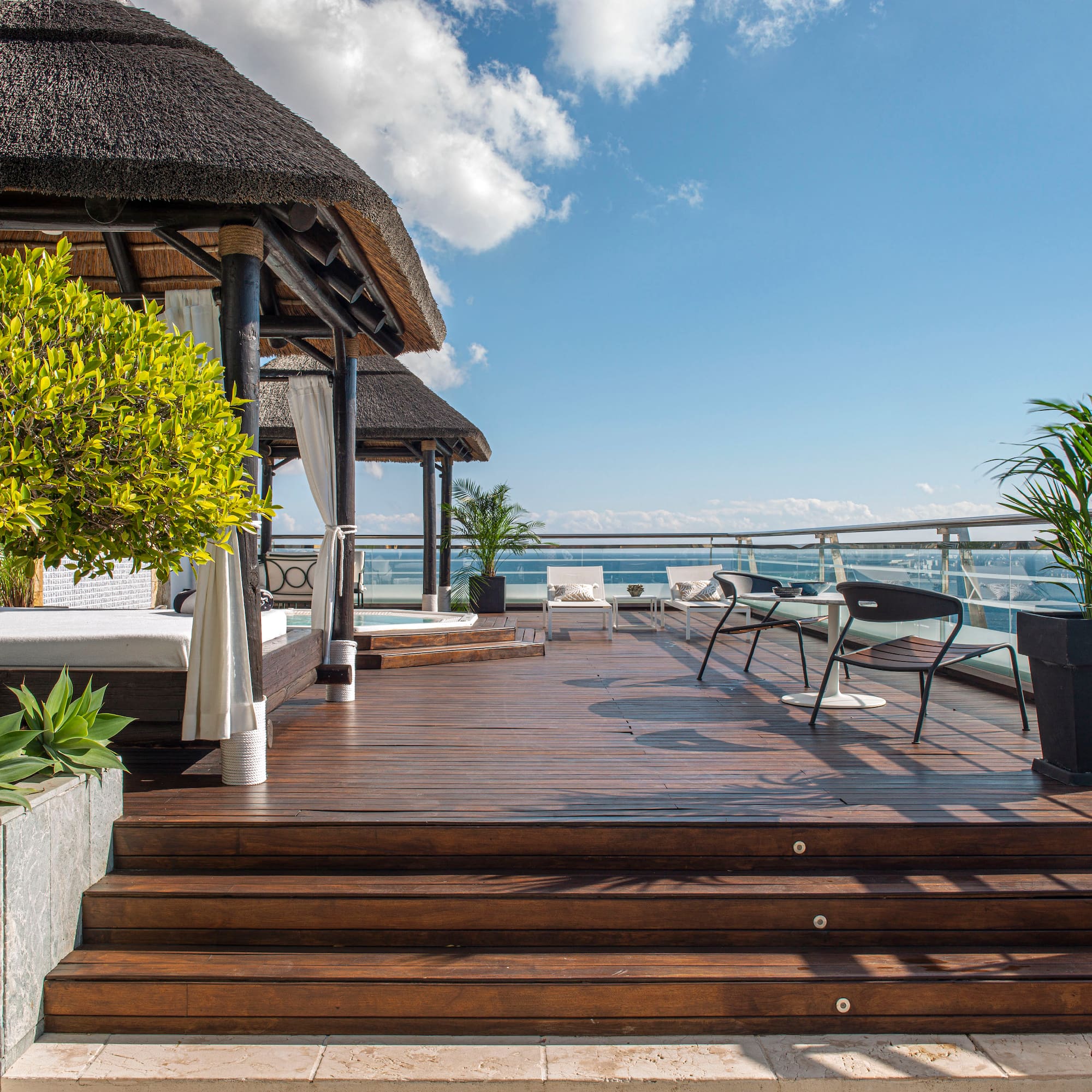a deck with a thatched roof and a thatched umbrella and chairs