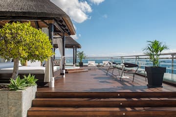 a deck with a thatched roof and a thatched umbrella and chairs