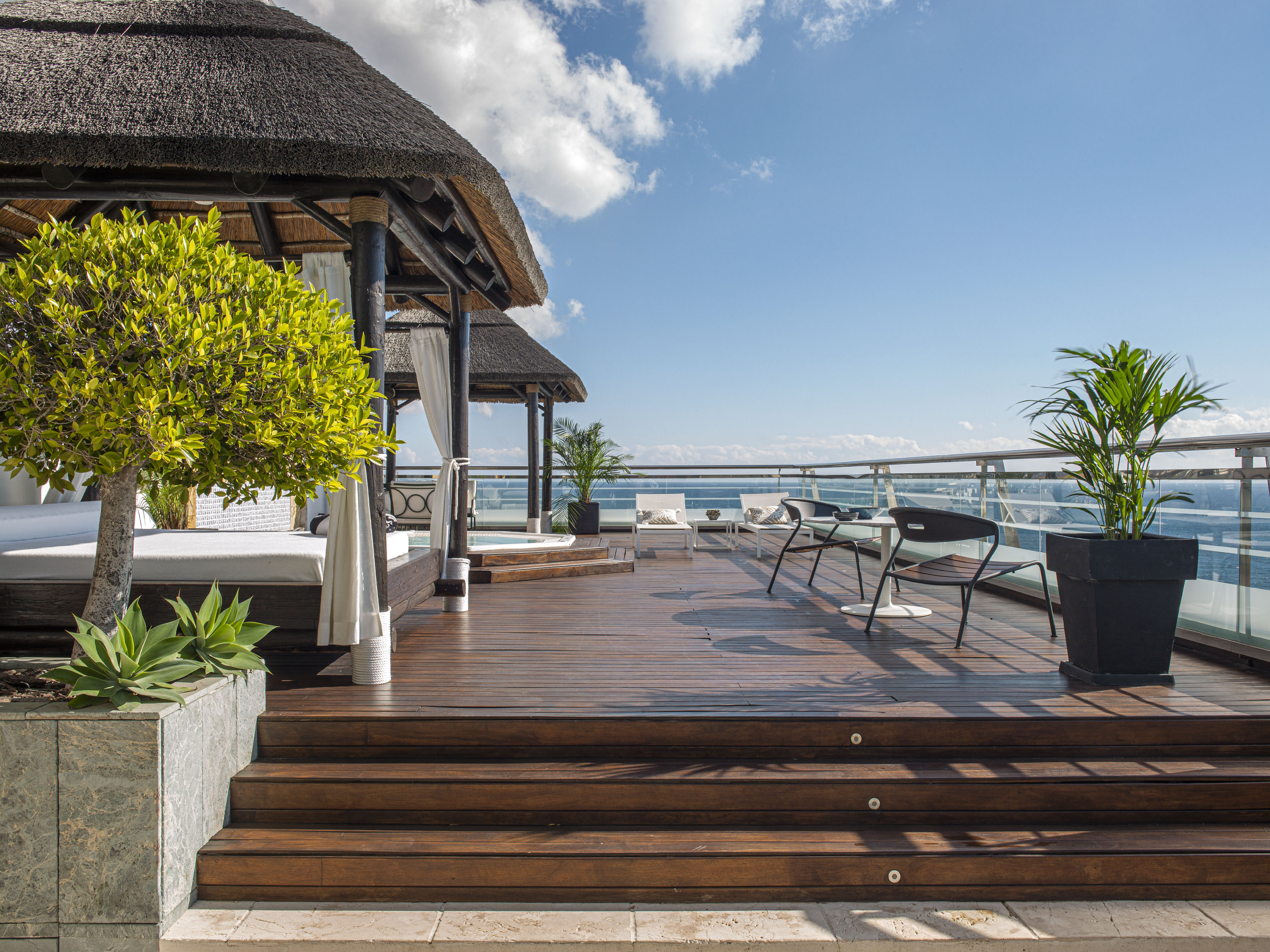 a deck with a thatched roof and a thatched umbrella and chairs