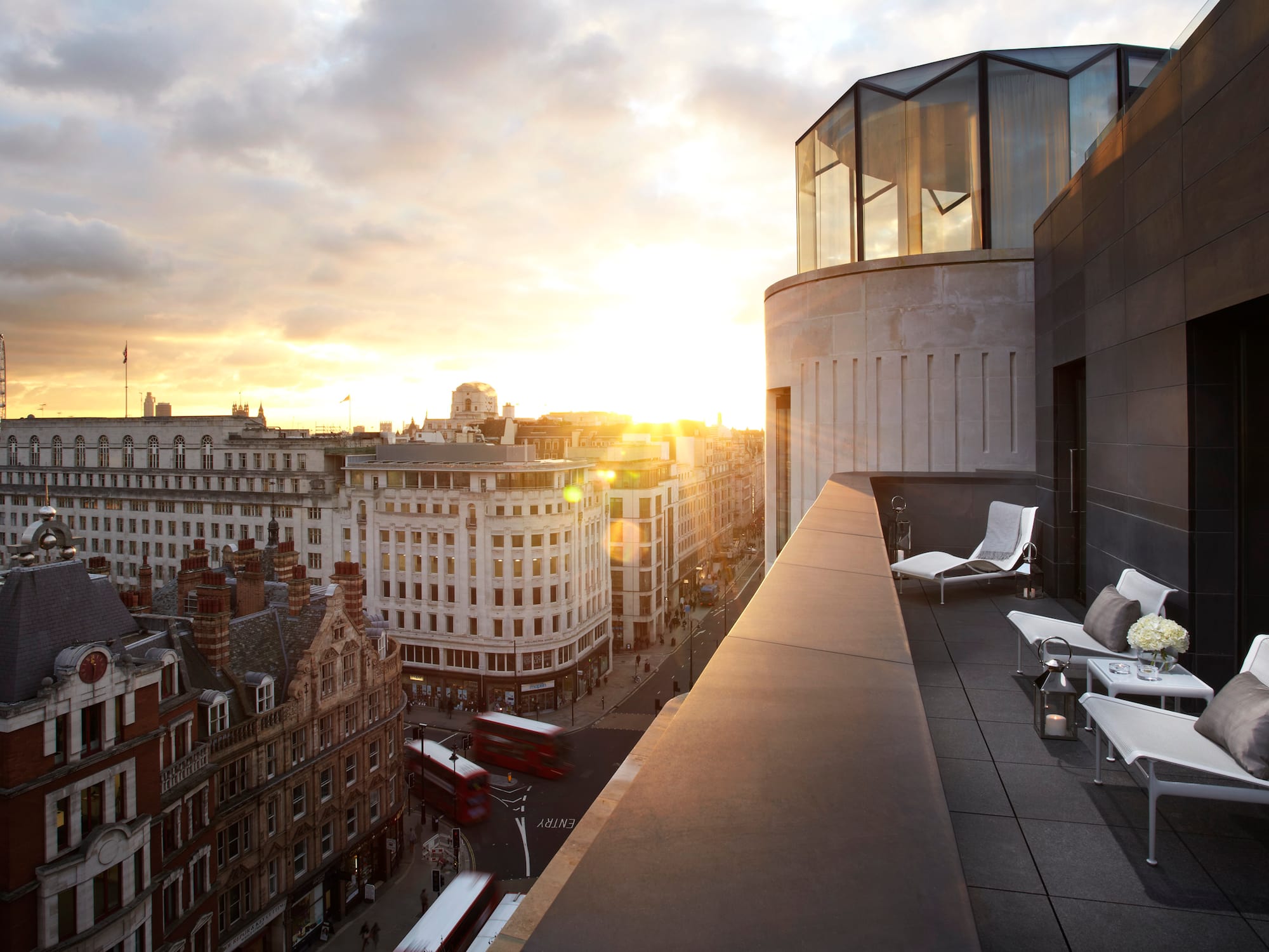 A city skyline viewed from a large glass balcony on the rooftop.