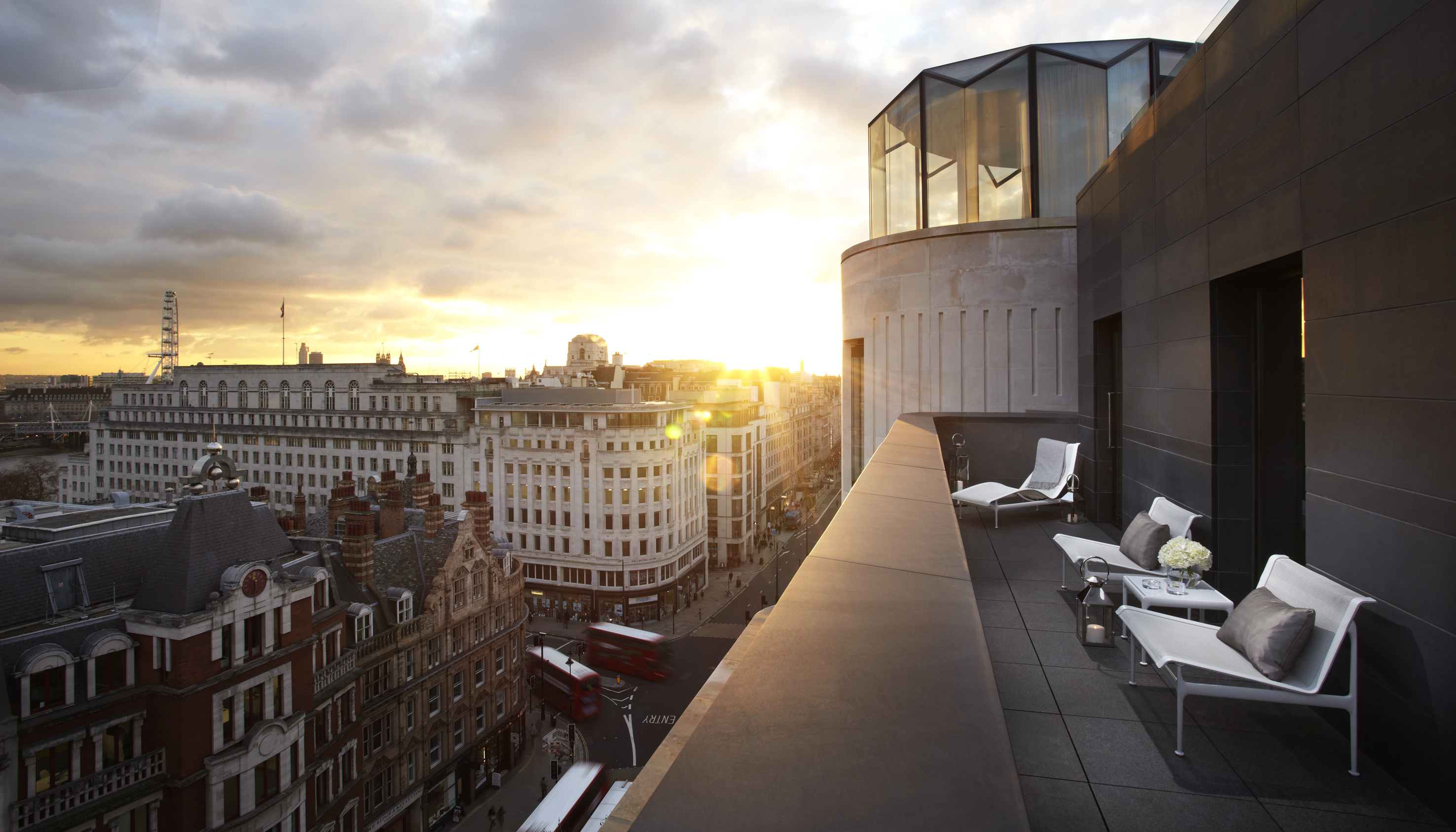 A city skyline viewed from a large glass balcony on the rooftop.