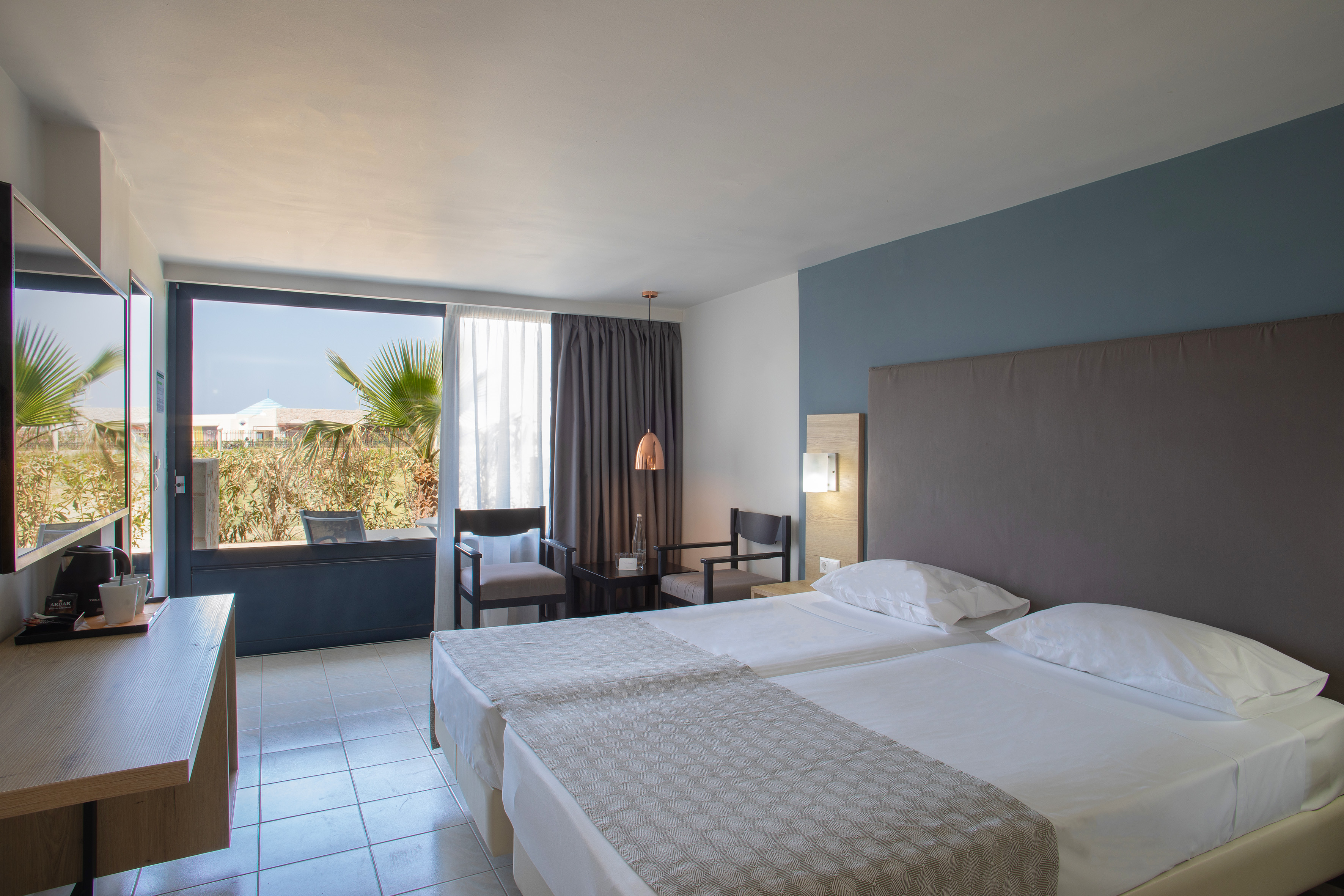Modern resort room with twin beds and tropical view.