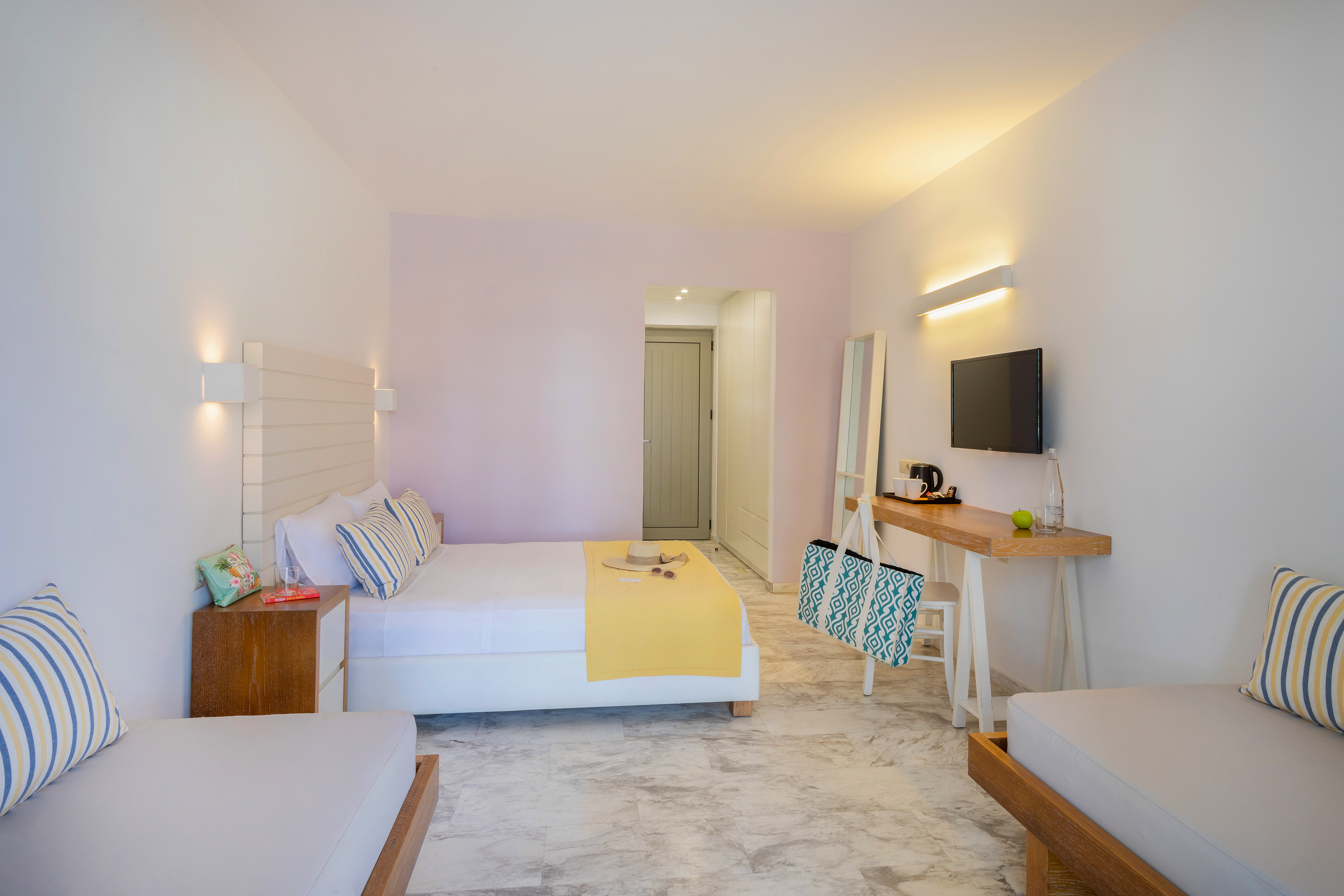 Bright, modern hotel bedroom with queen bed, desk, TV, and marble floor.