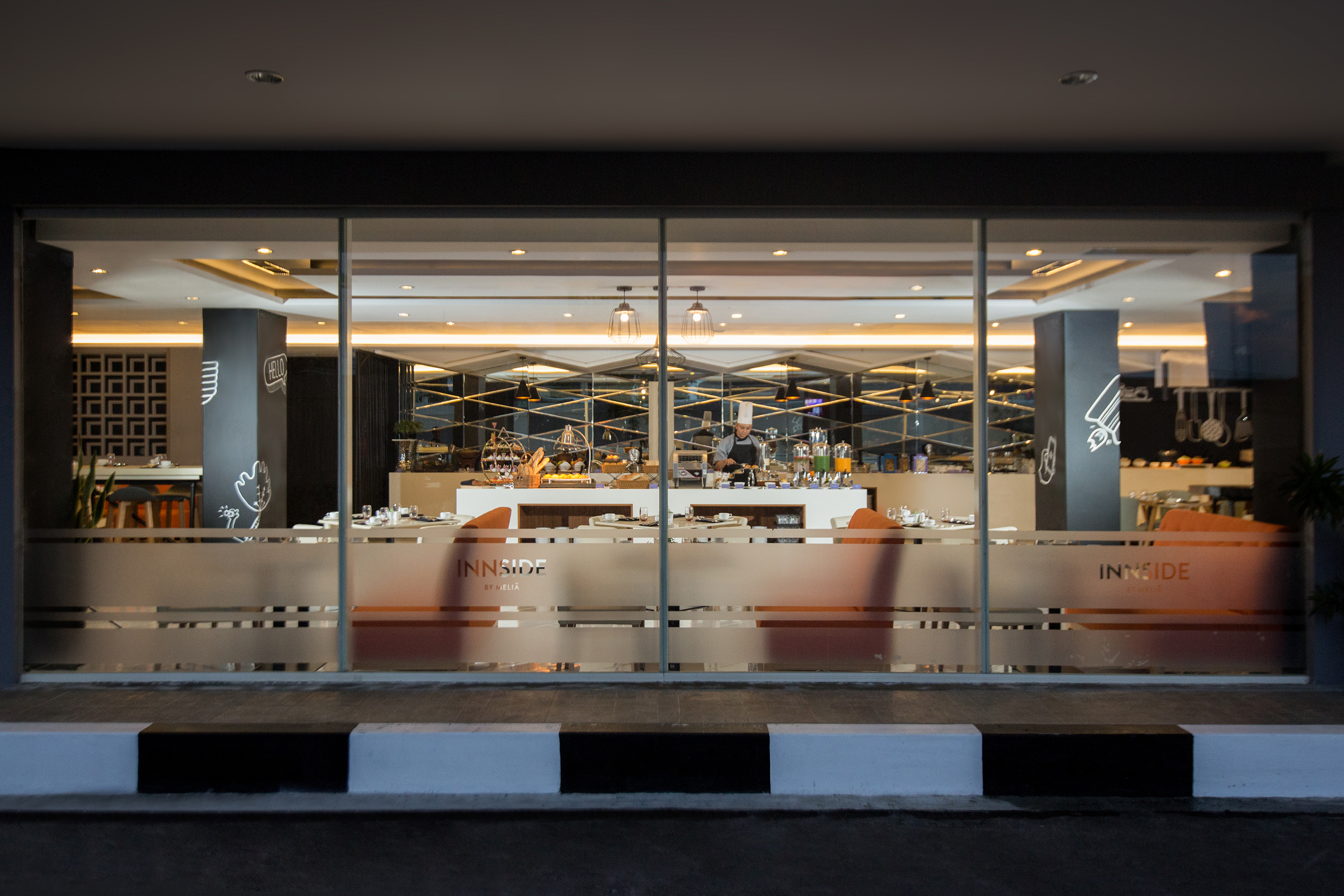 Modern Innside by Melia hotel restaurant buffet with chef and dining tables.