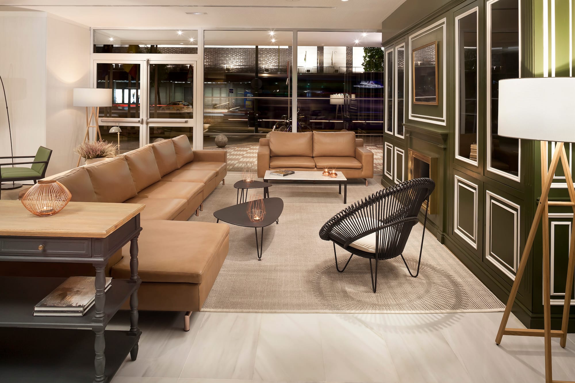 Modern lounge, brown leather sofas, black chair, green panels, and city night view.