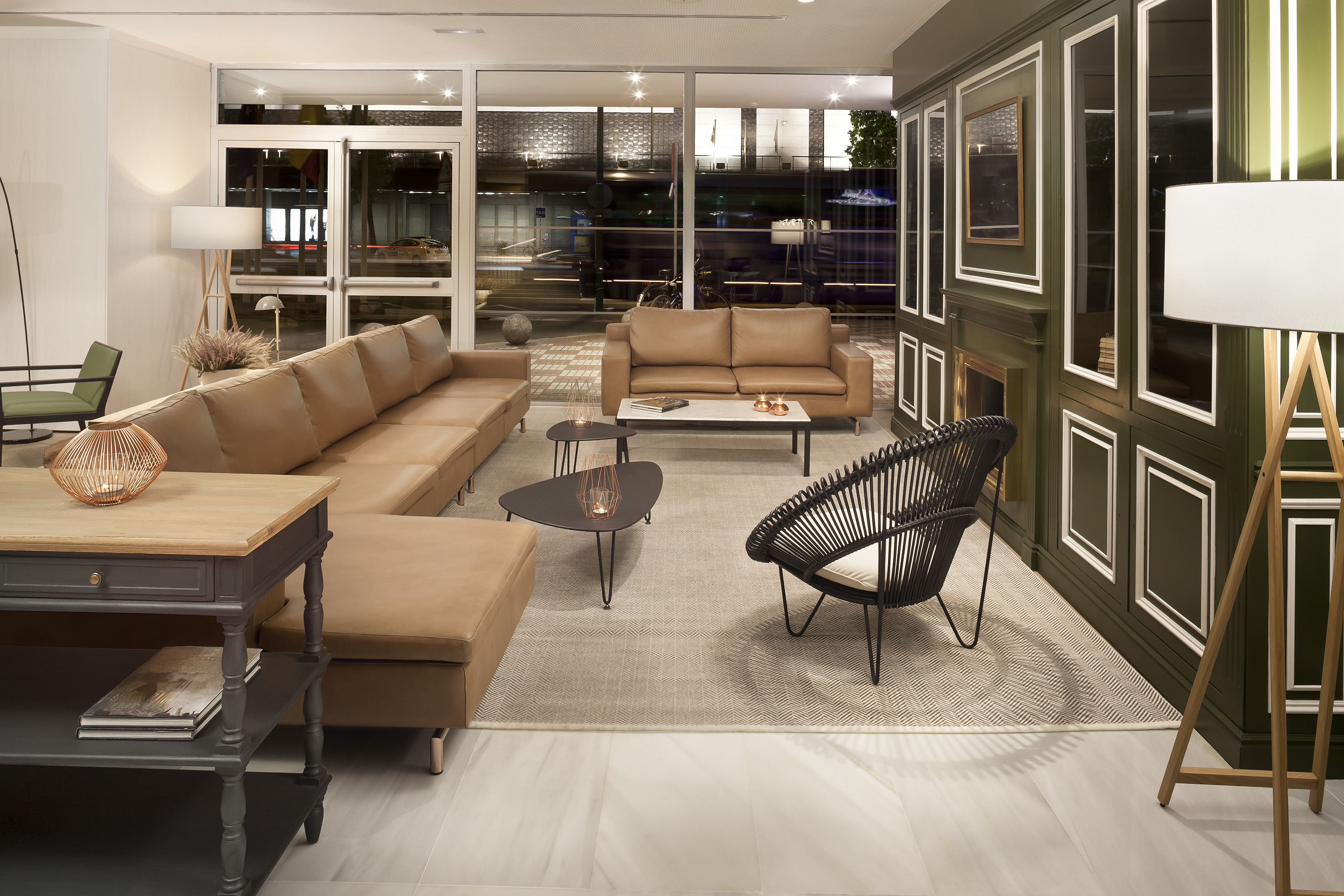 Modern lounge, brown leather sofas, black chair, green panels, and city night view.