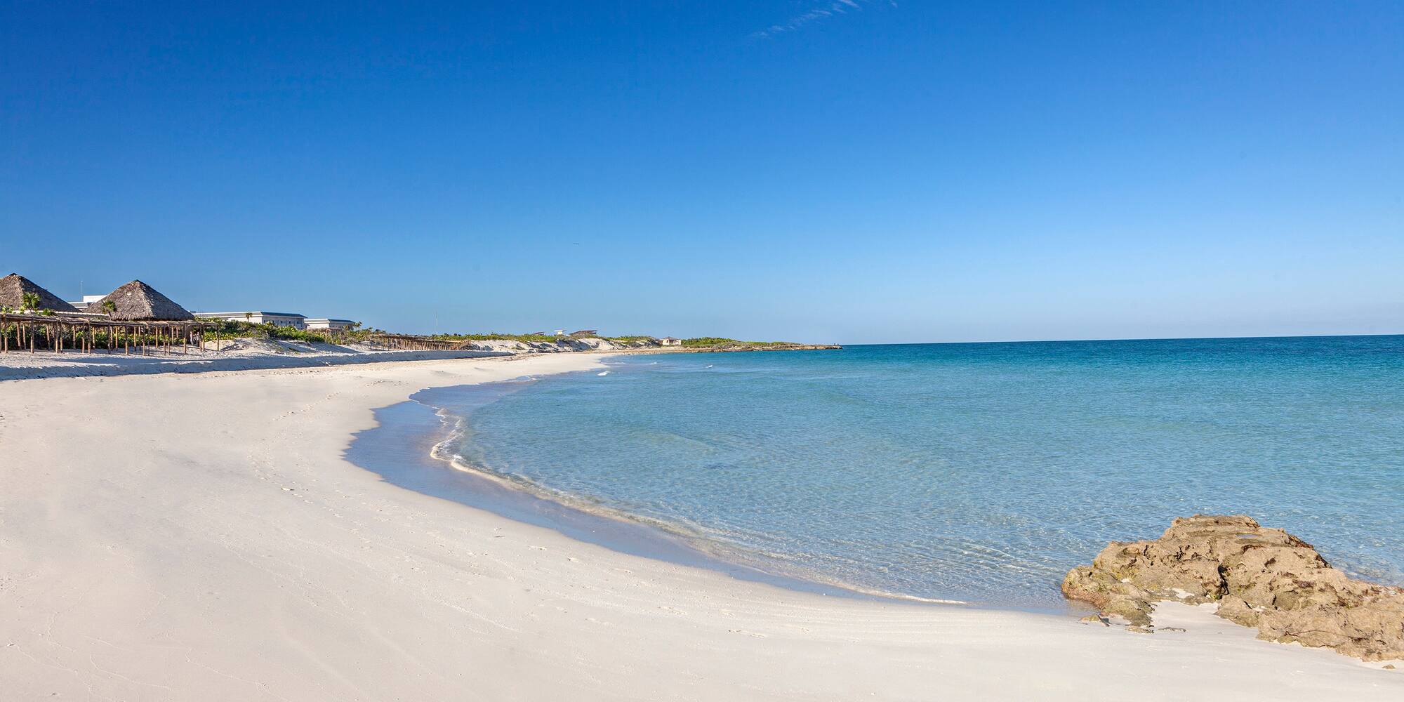 a beach with a body of water and a rock