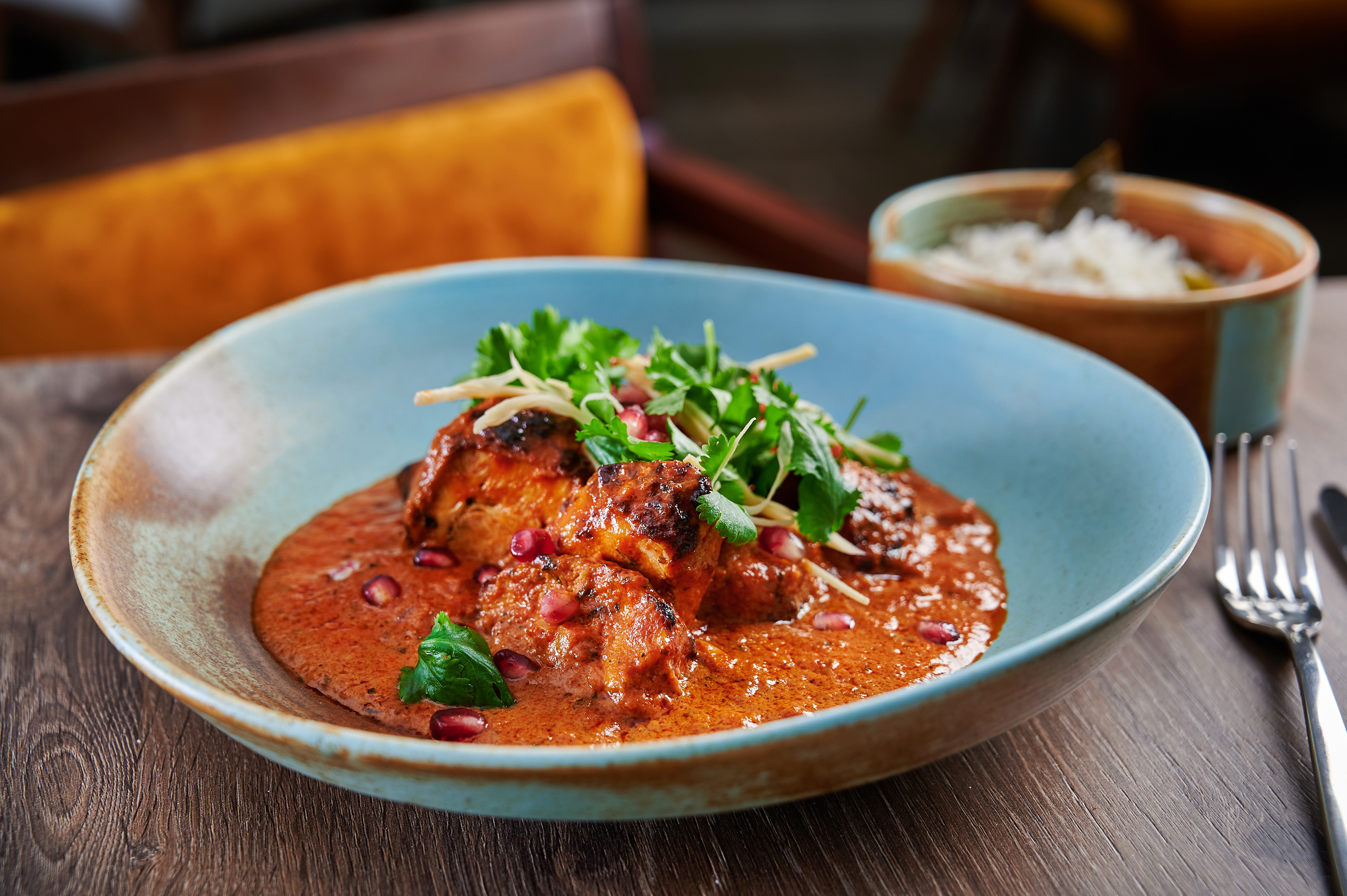 Indian chicken curry with cilantro, pomegranate, and ginger garnish.