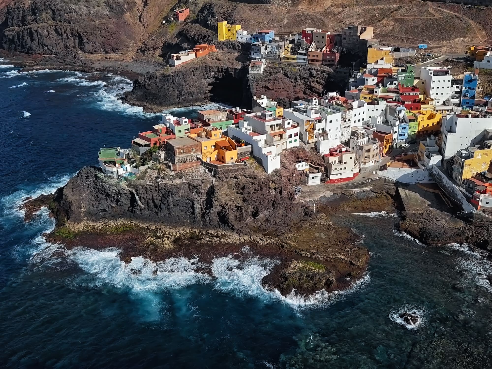 Colorful coastal village on rocky cliffs by the ocean, vibrant houses.