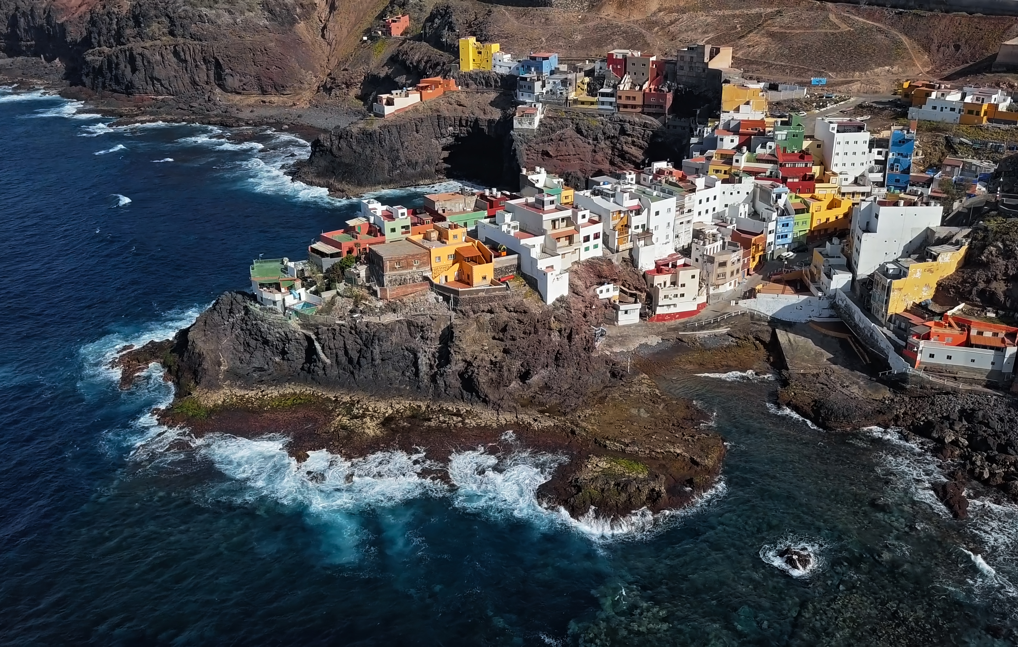 Colorful coastal village on rocky cliffs by the ocean, vibrant houses.