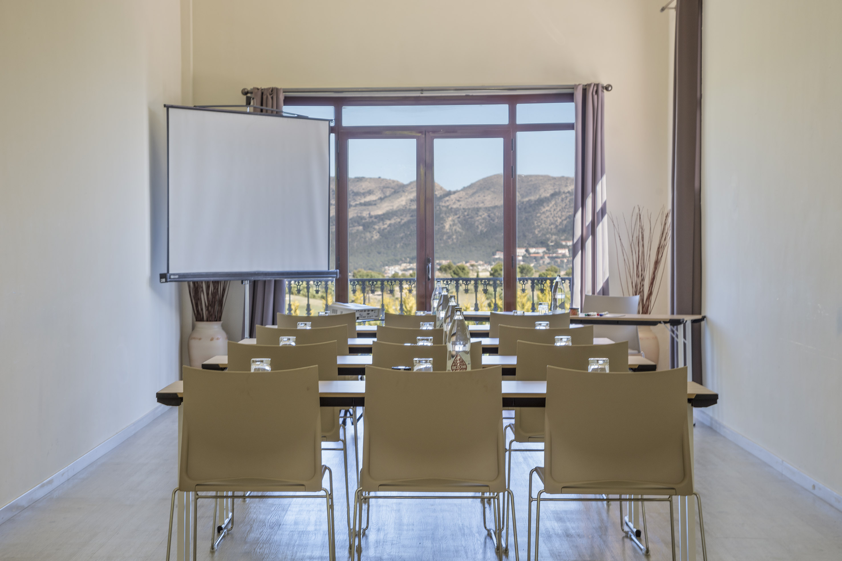 Empty conference room with projector screen, row seating, and mountain view.