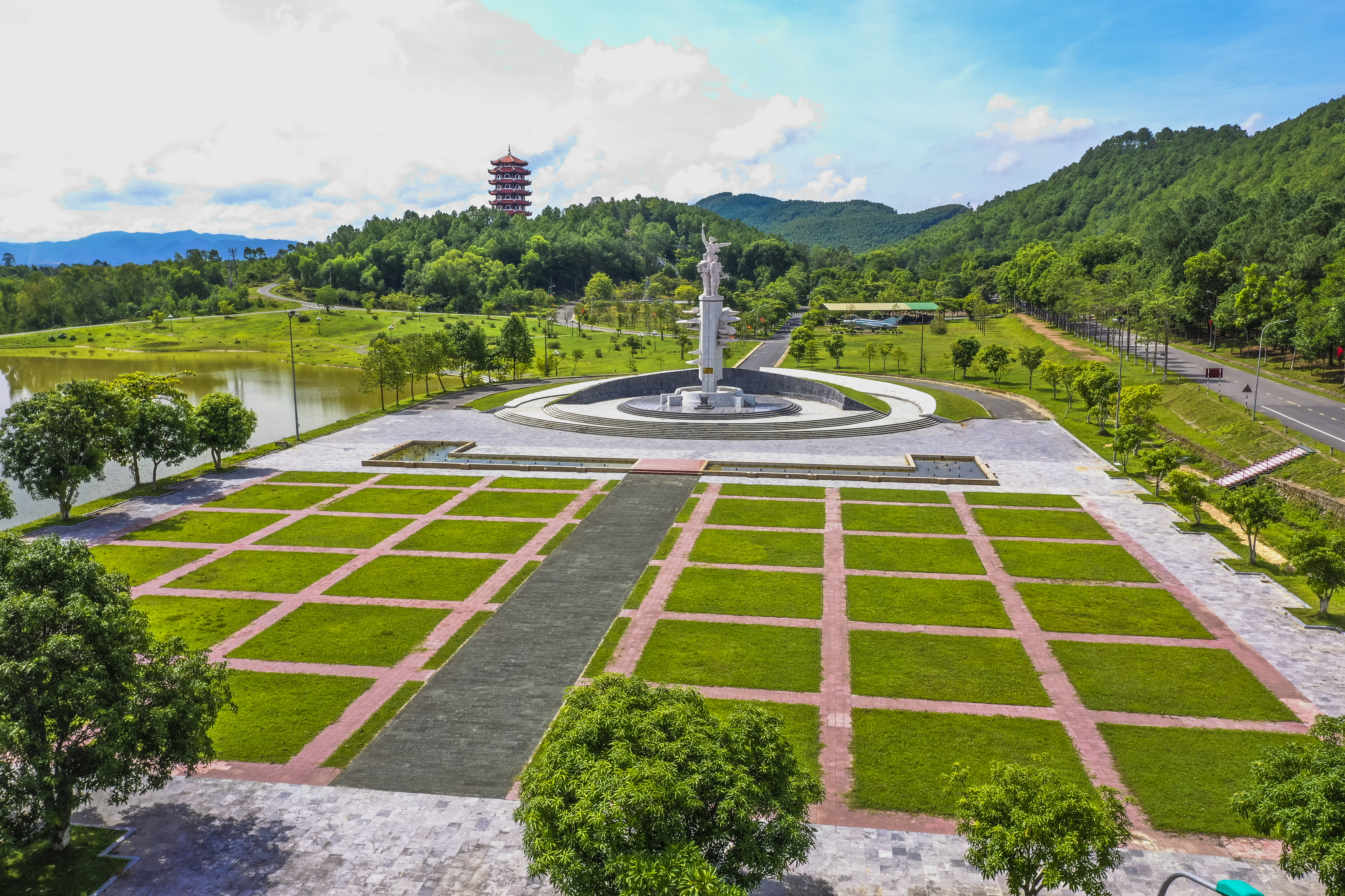 a large white statue in a park with a pond and trees