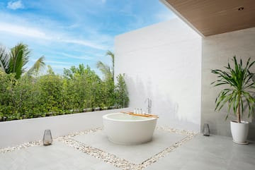 a bathtub outside with a white wall and plants