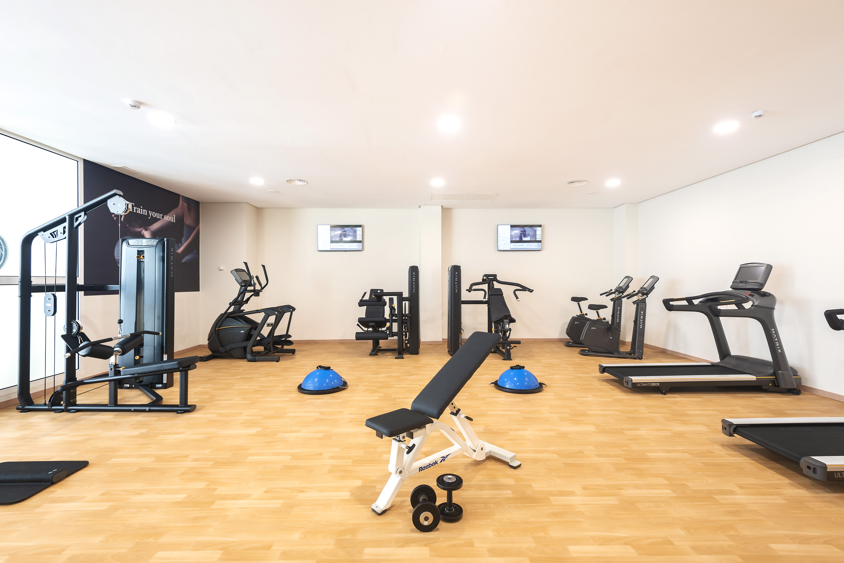 Modern hotel fitness center with cardio and weight training equipment.