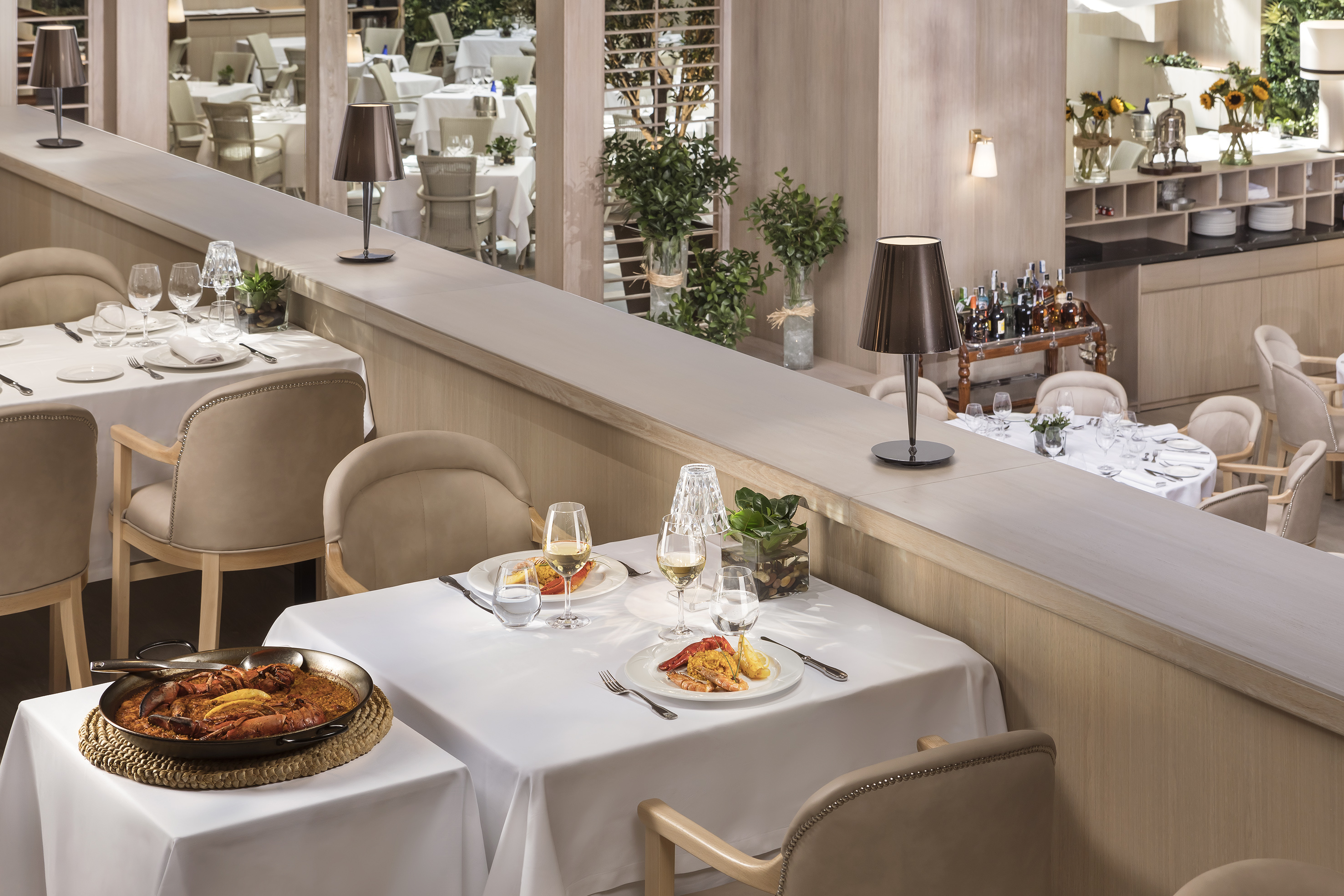 Elegant restaurant dining room with seafood paella and plated dishes.