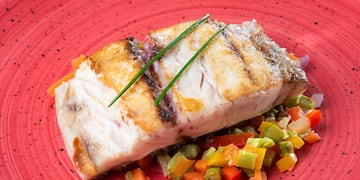 a piece of fish with vegetables on a red plate