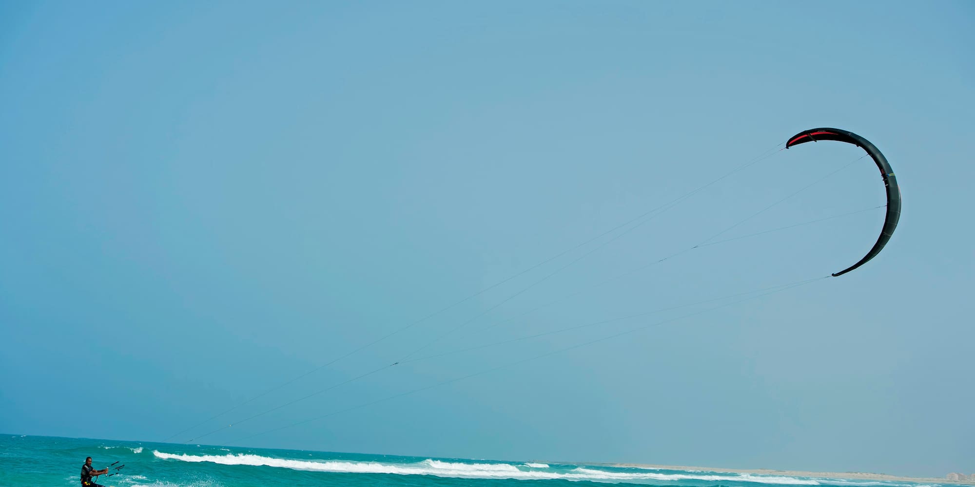 a person flying a kite over the ocean