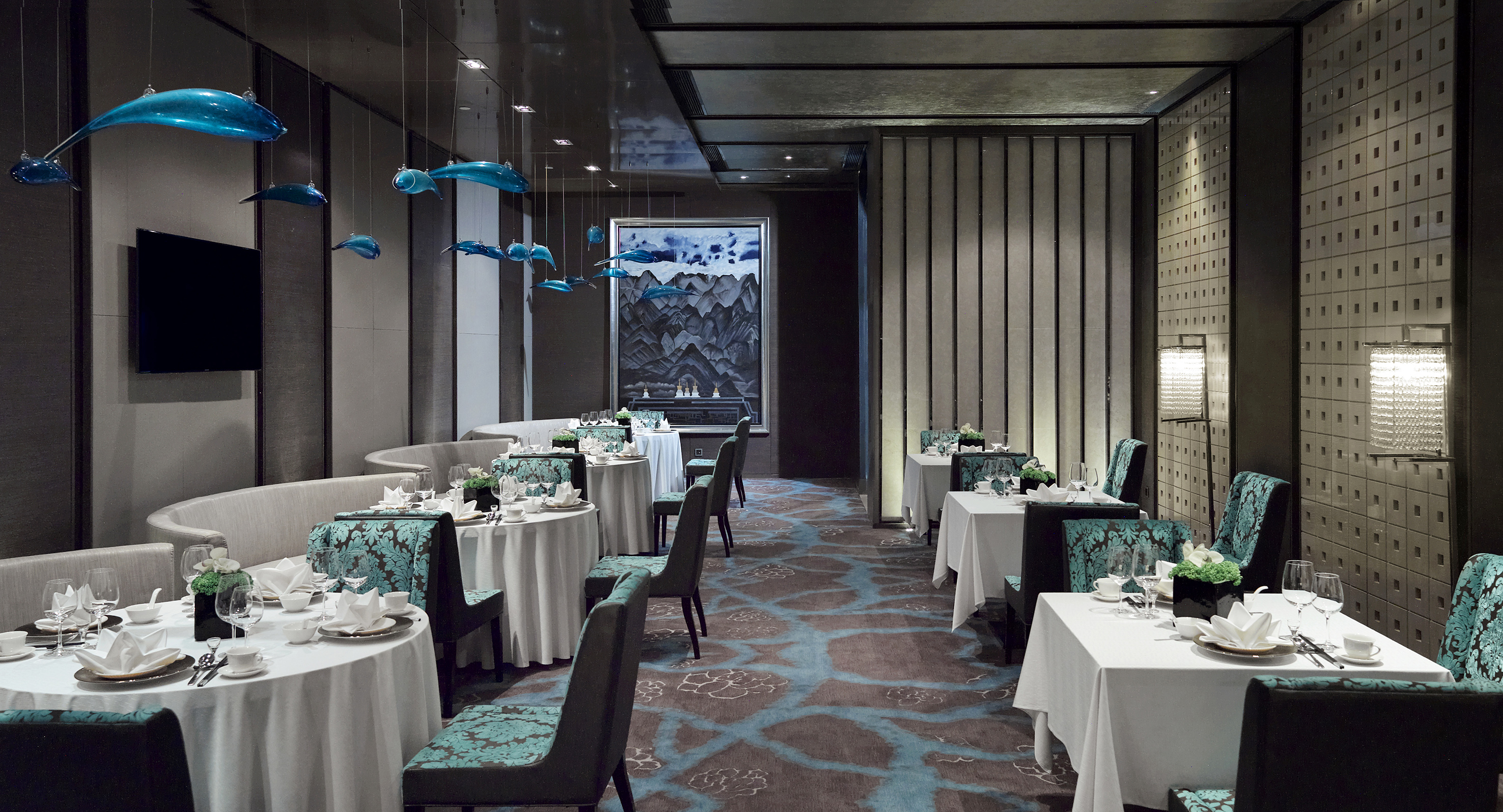 Elegant restaurant interior with set tables, teal chairs, and blue glass dolphin art.
