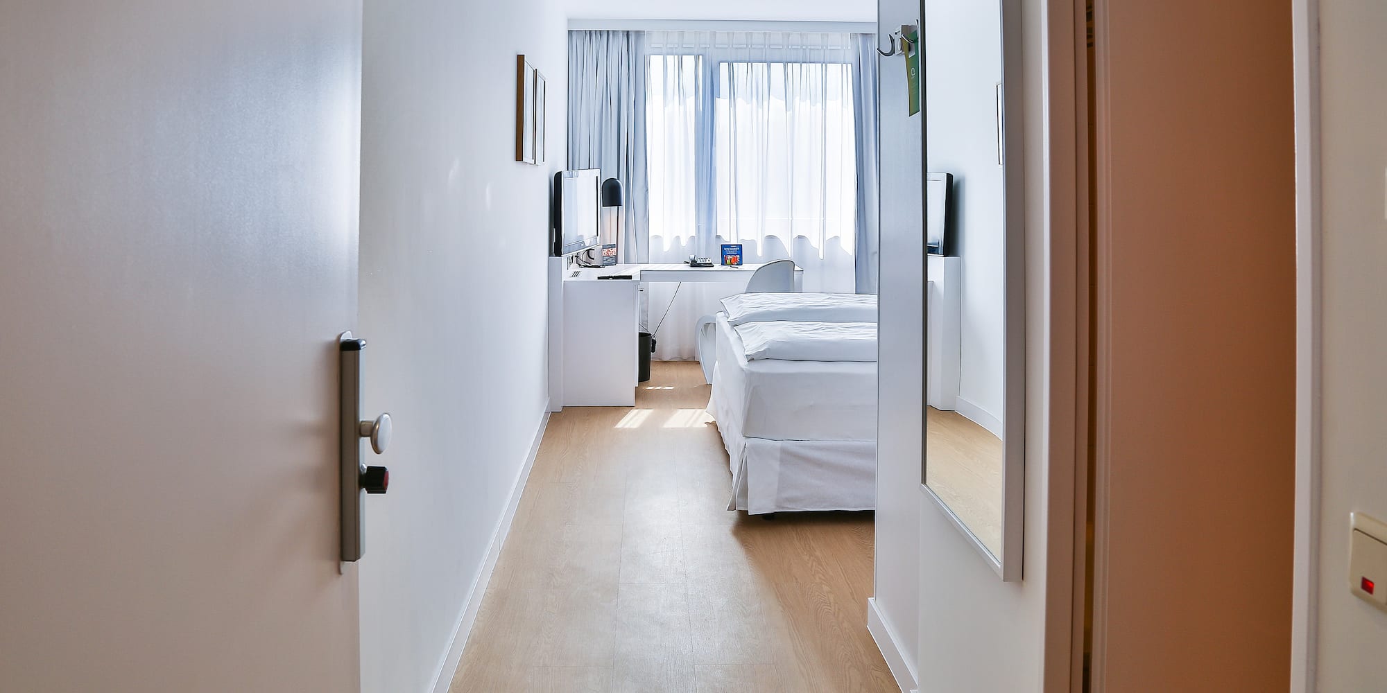 a hallway with a bed and a mirror