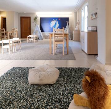 a room with a large carpet and chairs and a toy lion