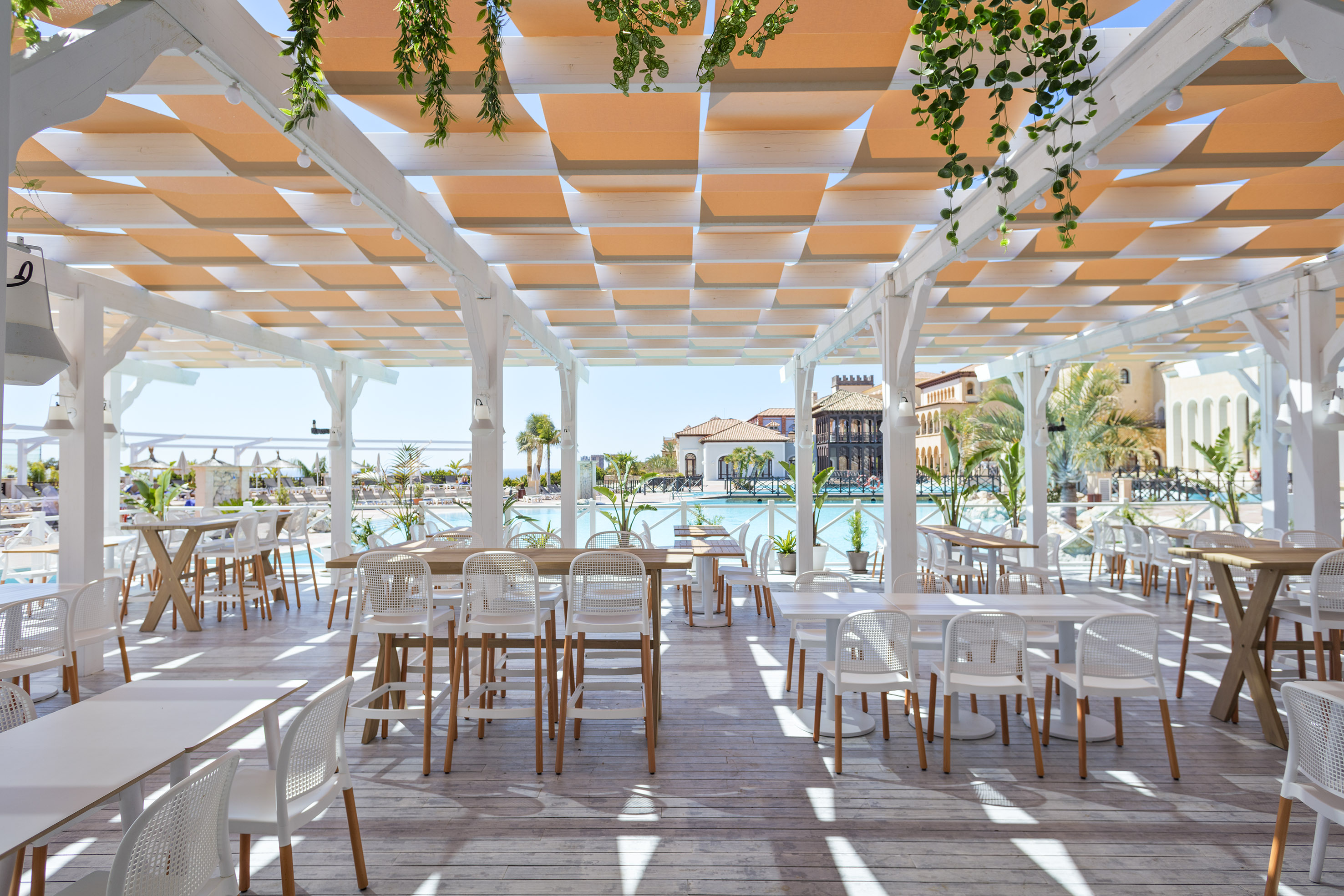 Outdoor resort restaurant patio, white pergola, orange shades, modern furniture.