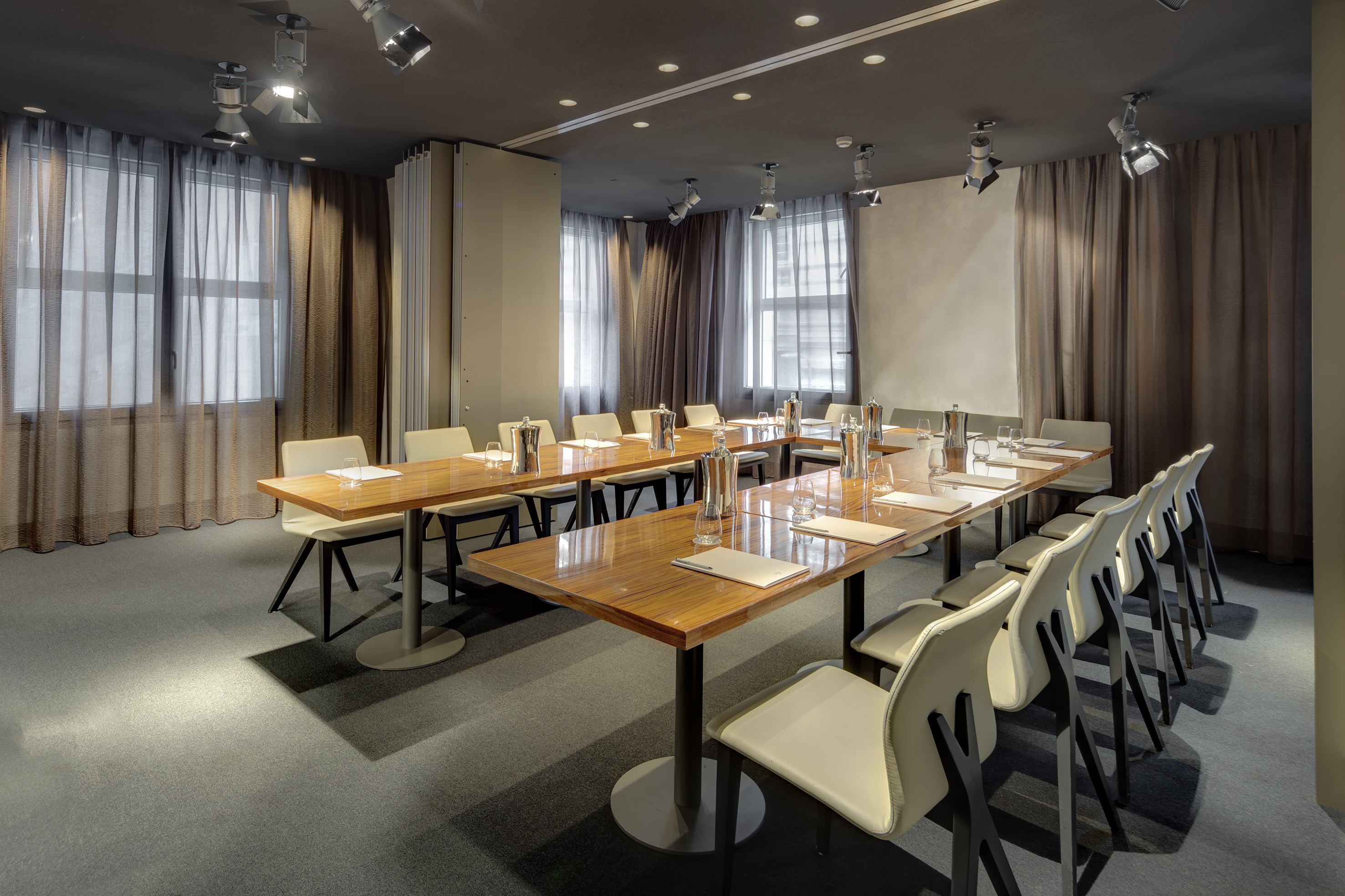 Modern meeting room with wooden tables, white chairs, and professional setup.