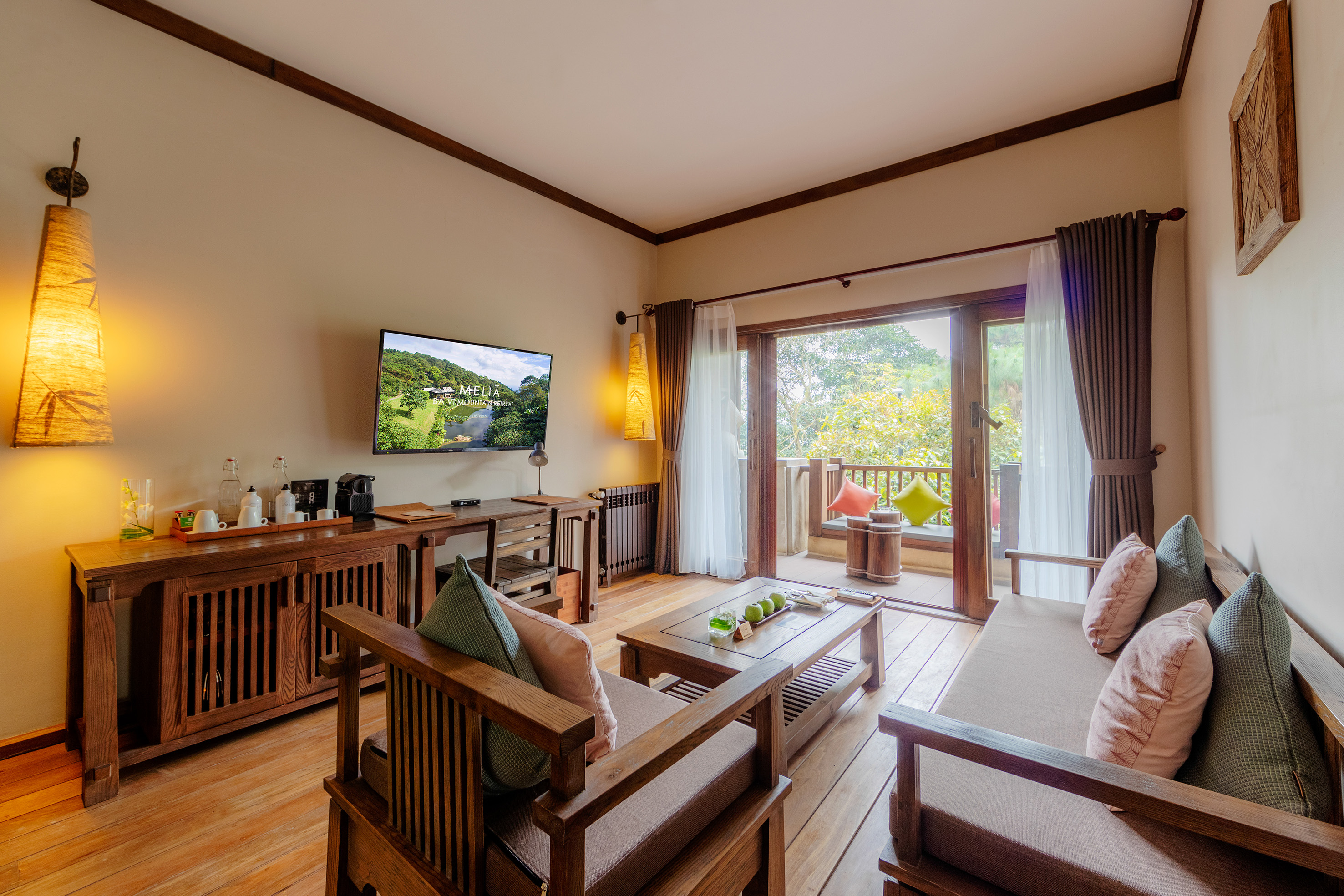 a living room with a television and a television on the wall - Junior Suite - Meliá Ba Vi Mountain Retreat, Hanói